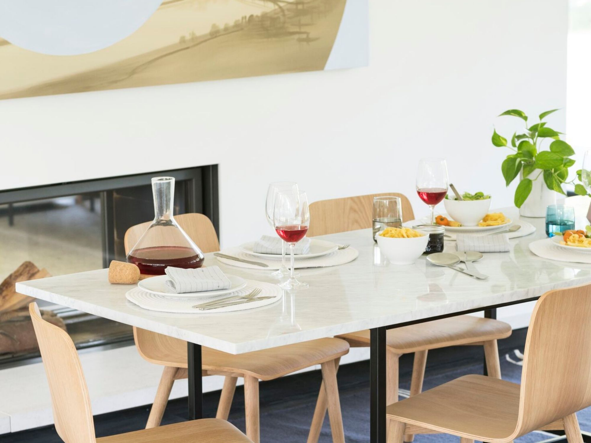 Red wine  glasses on a dining table with plates, flatware, and decanter