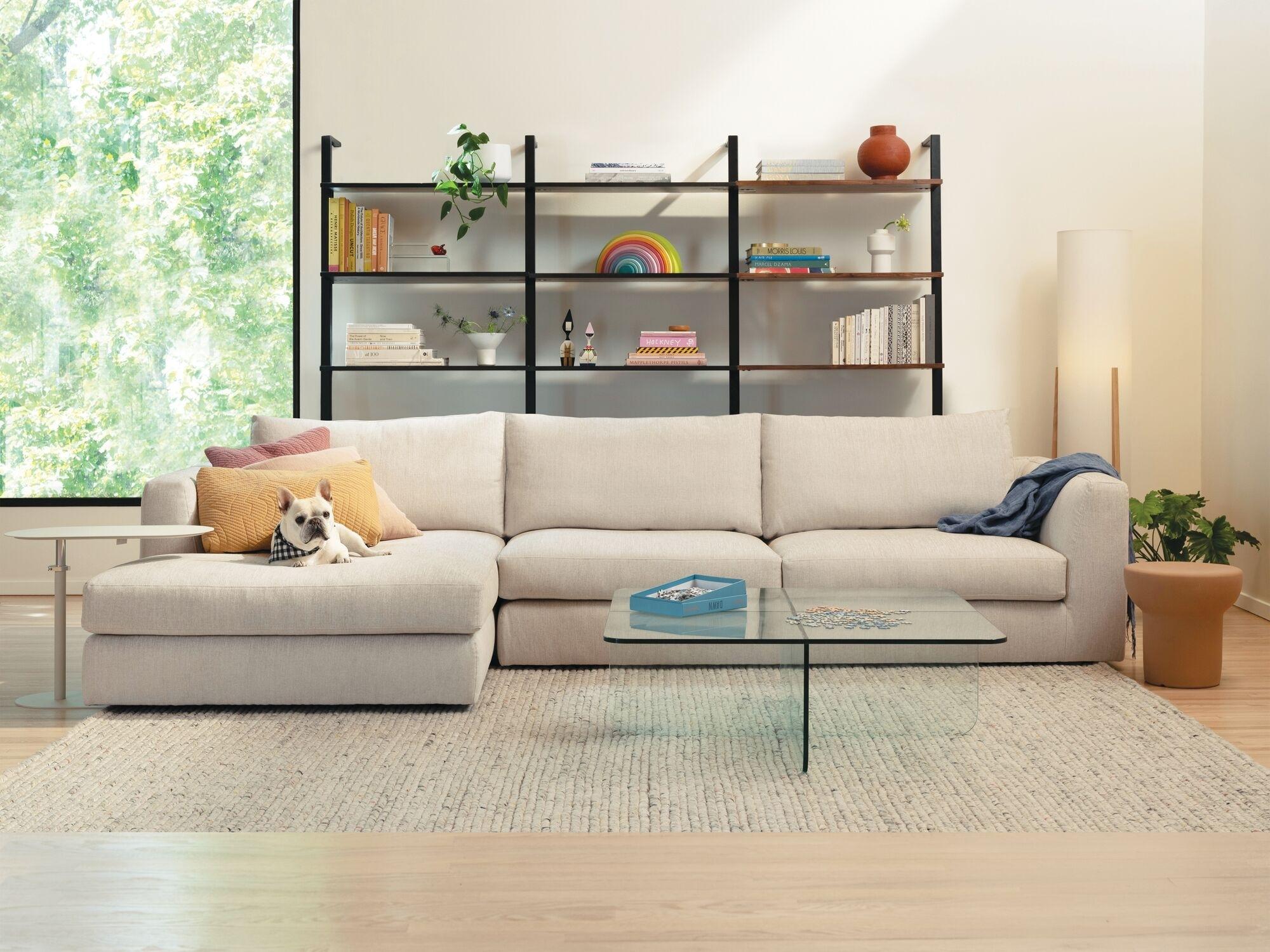 Beige sectional with glass coffee table and beige rug in bright, modern living room