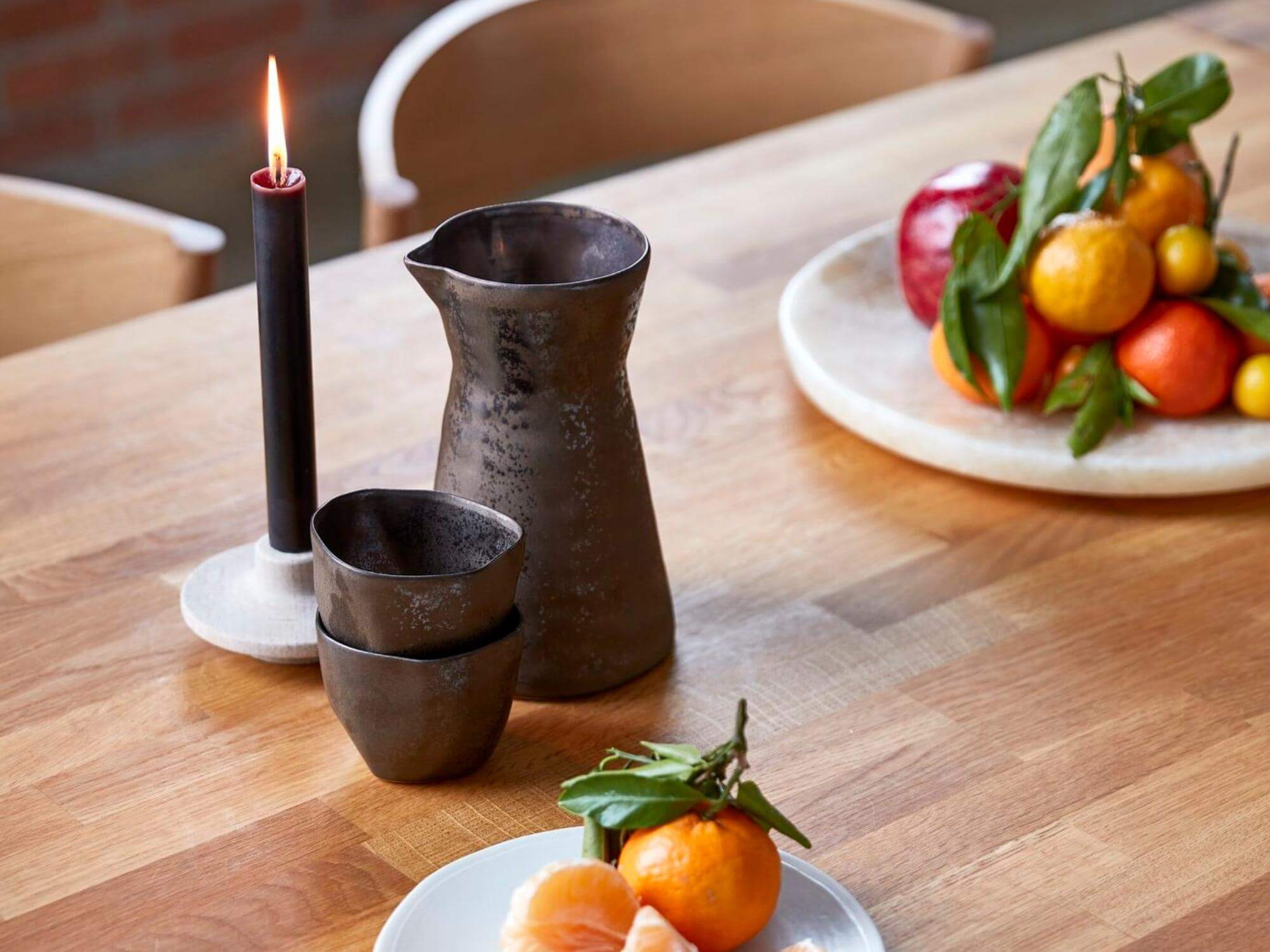 Brown stoneware carafe on oak dining table set for dinner