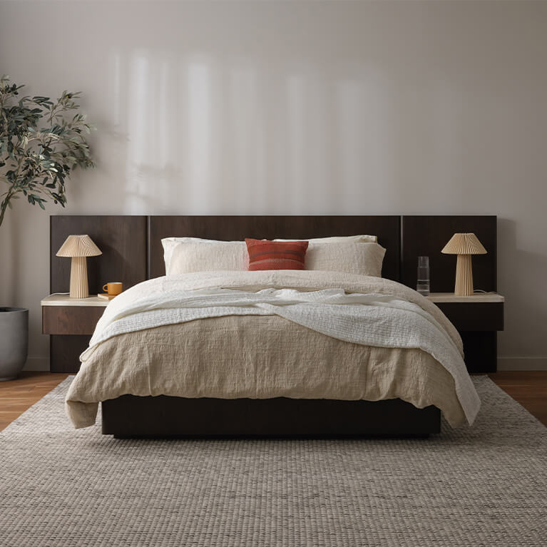 Un lit en chêne fumé est présenté dans un salon moderne. Lien vers la catégorie Lits