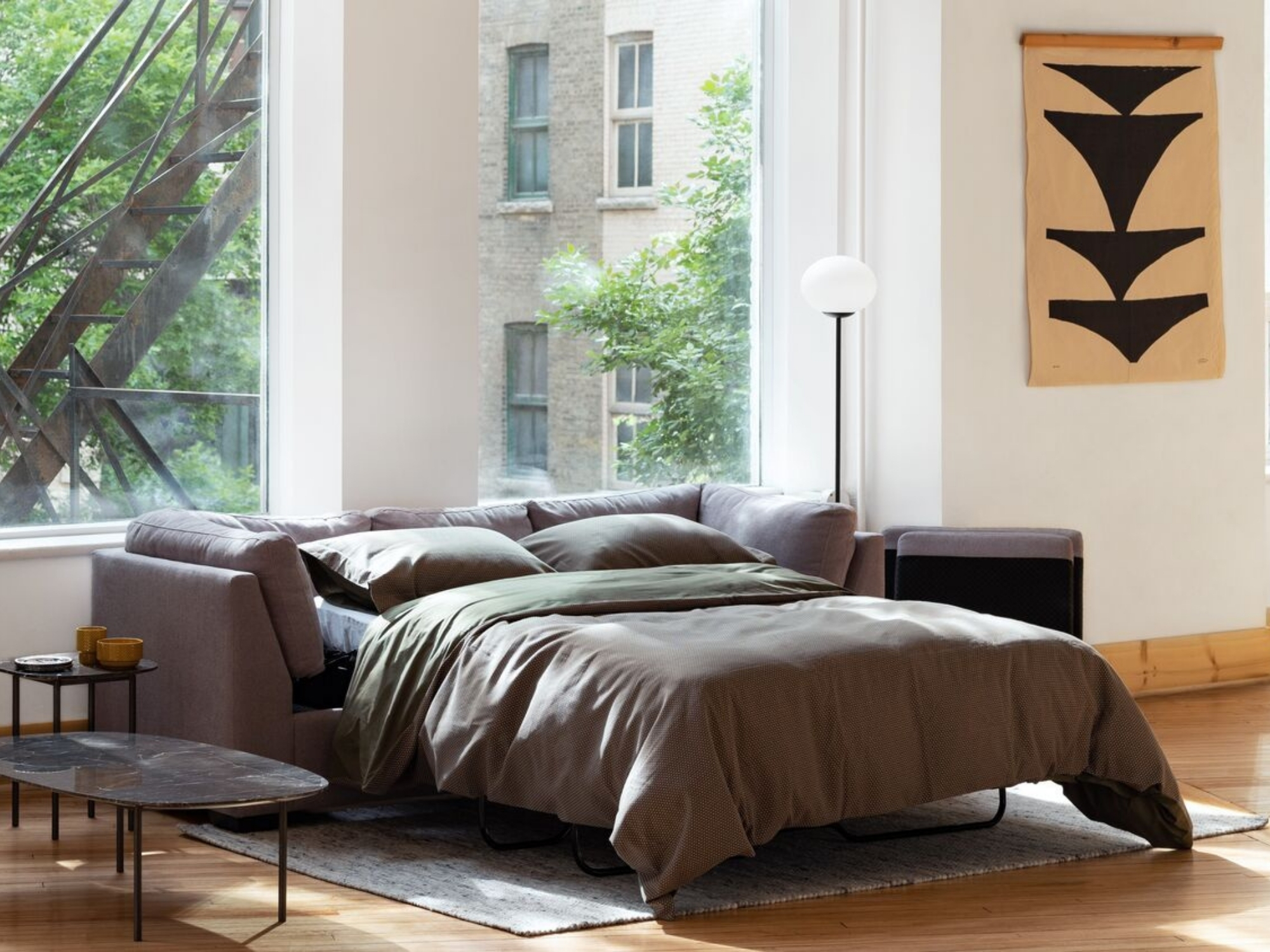 White shaded modern floor lamp next to open sofa bed