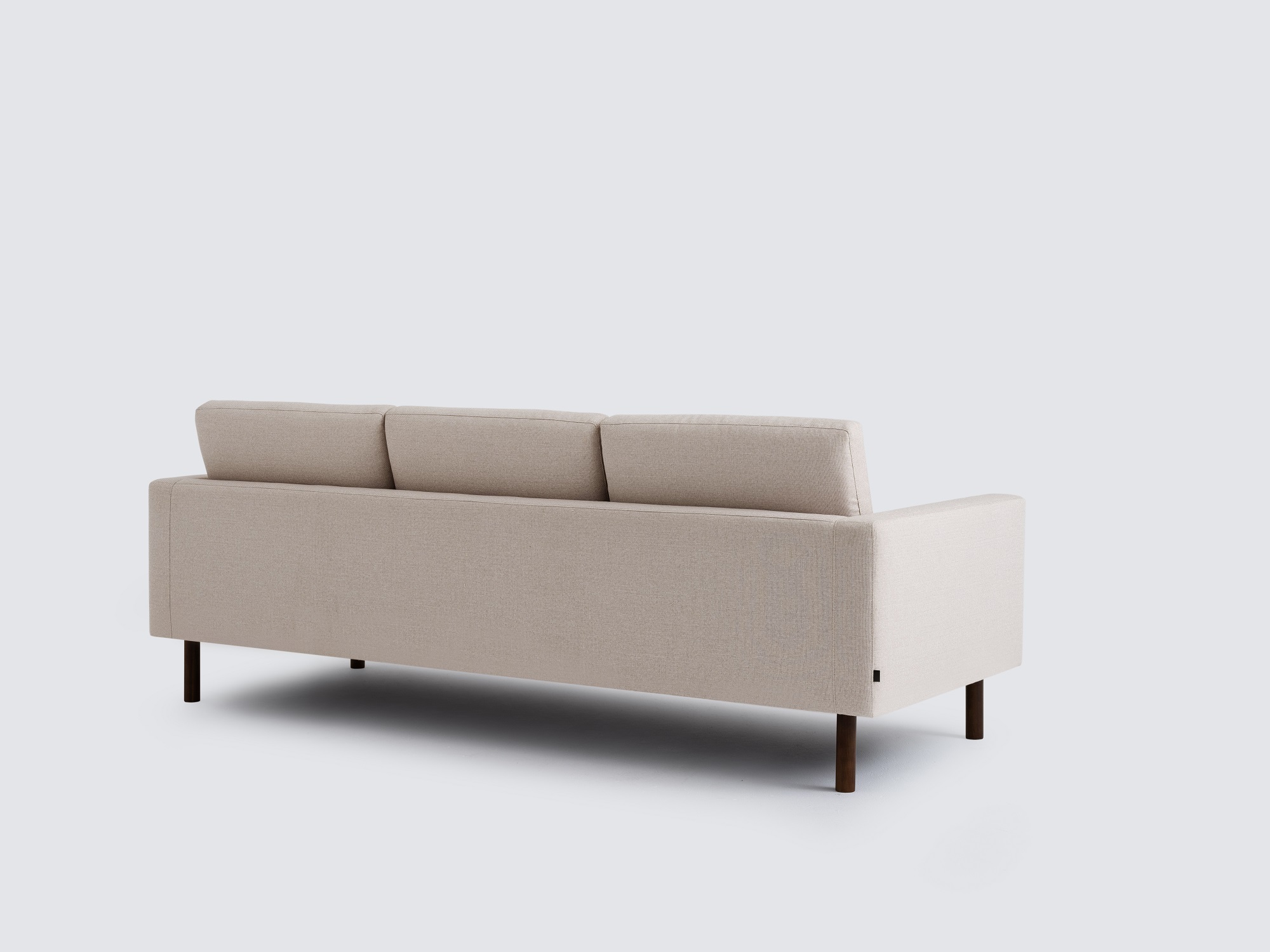 Back angled view of the Joan long modern sofa upholstered in beige fabric