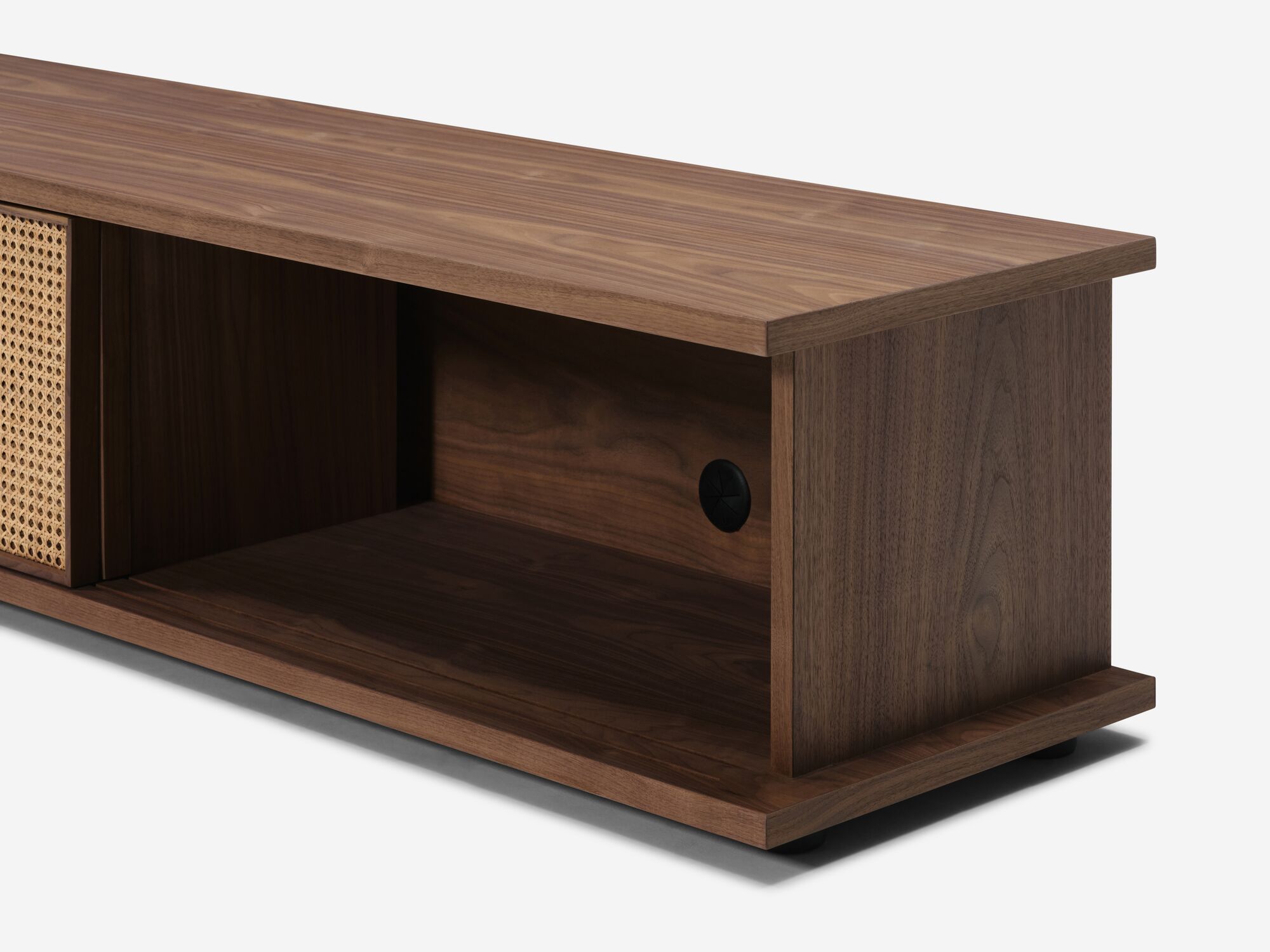 Detail view of low walnut media unit with open natural cane doors