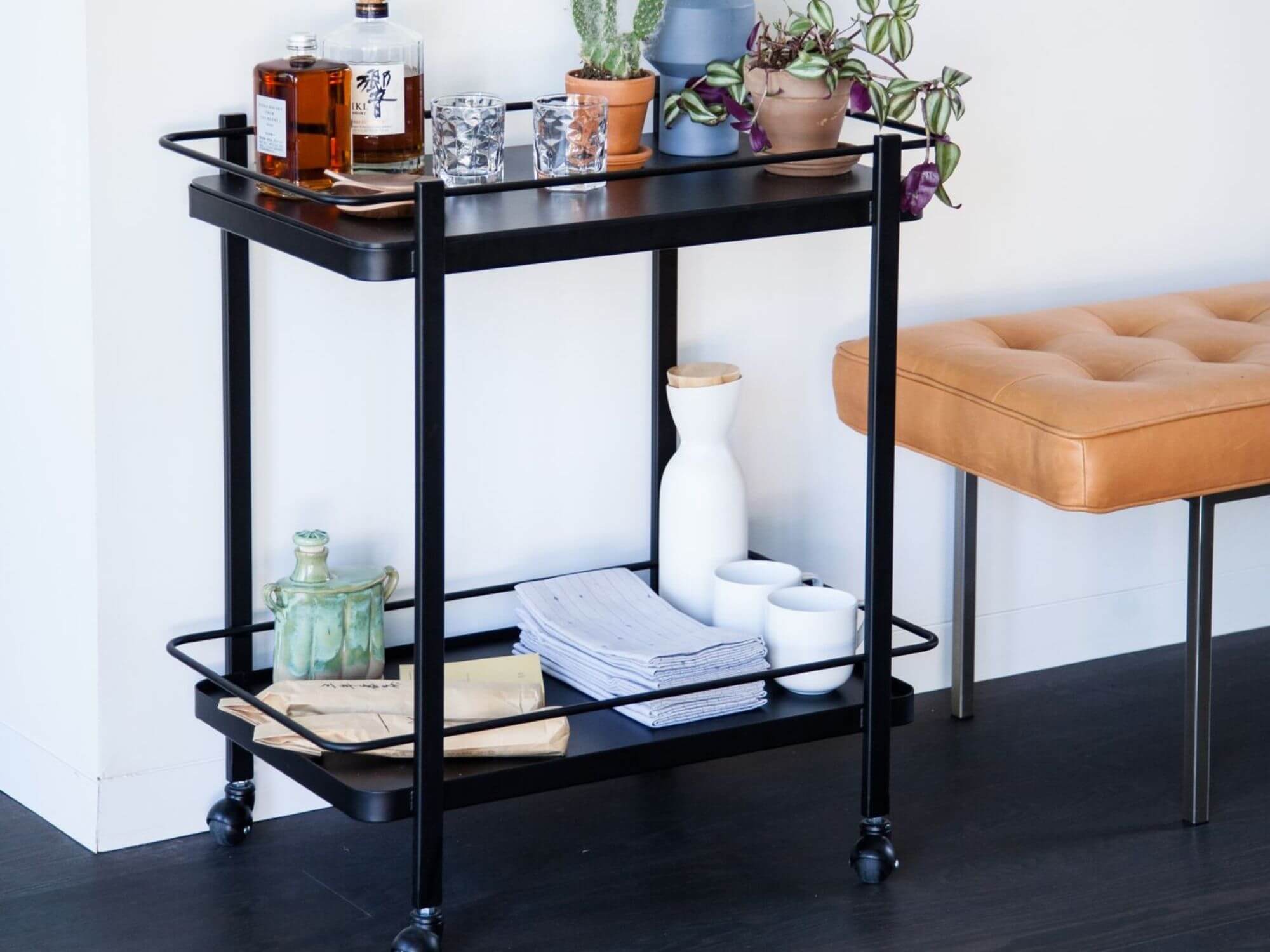 White stoneware milk jug on black finished bar cart with barware and bouquets on it