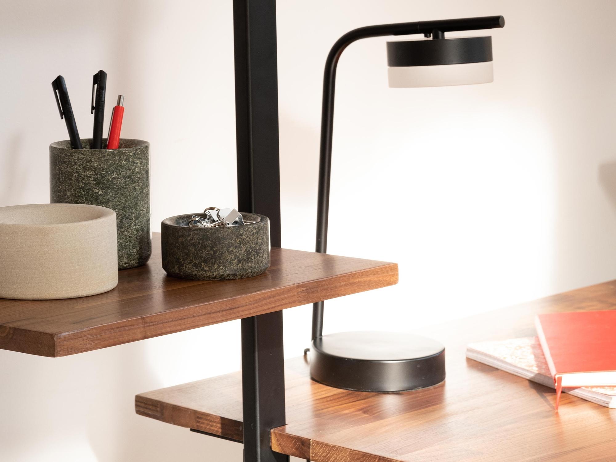 Modern black table lamp on open bookcase desk in home workspace