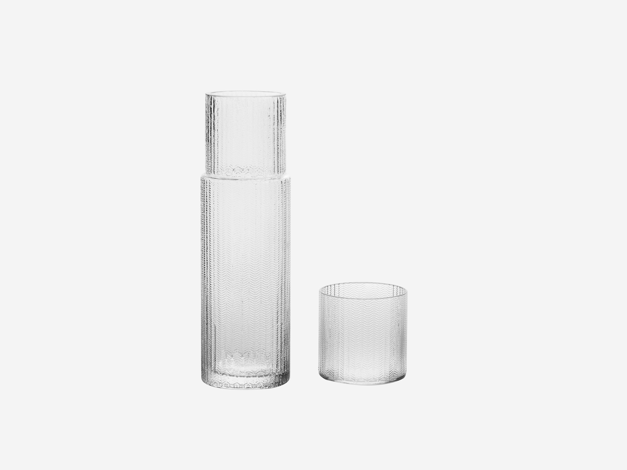 Clear glass carafe with cup beside it