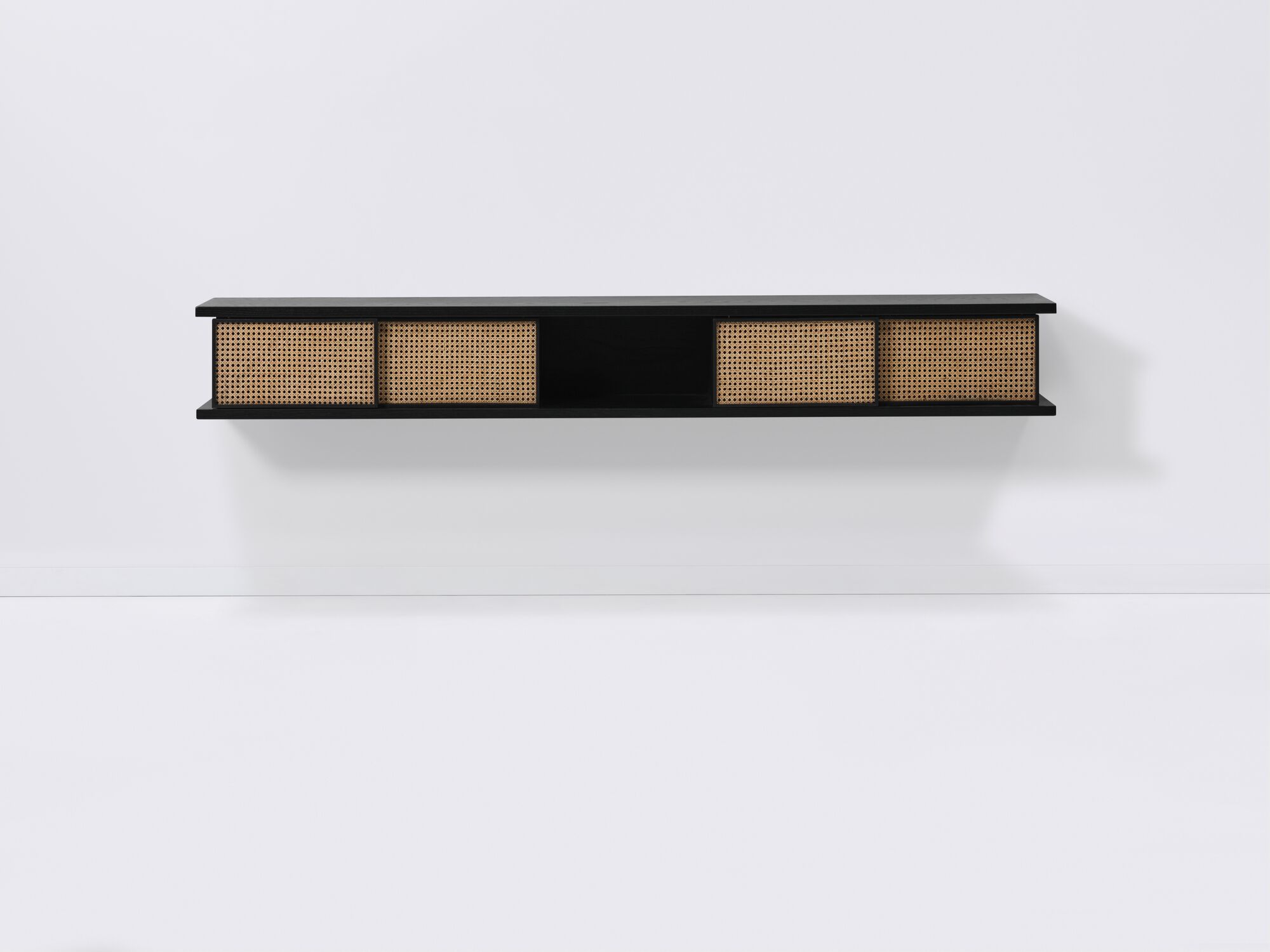 Front view of long black floating shelf with natural cane doors