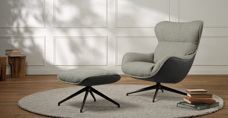 Un fauteuil d'appoint gris et son pouf assorti sont exposés dans un salon. Lien vers le revêtement prêt à être expédié.