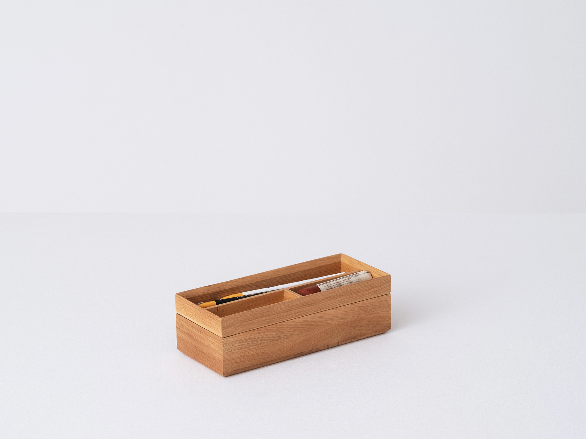 Angled view of the small Draft Pencil Box in oak with pencils in the top