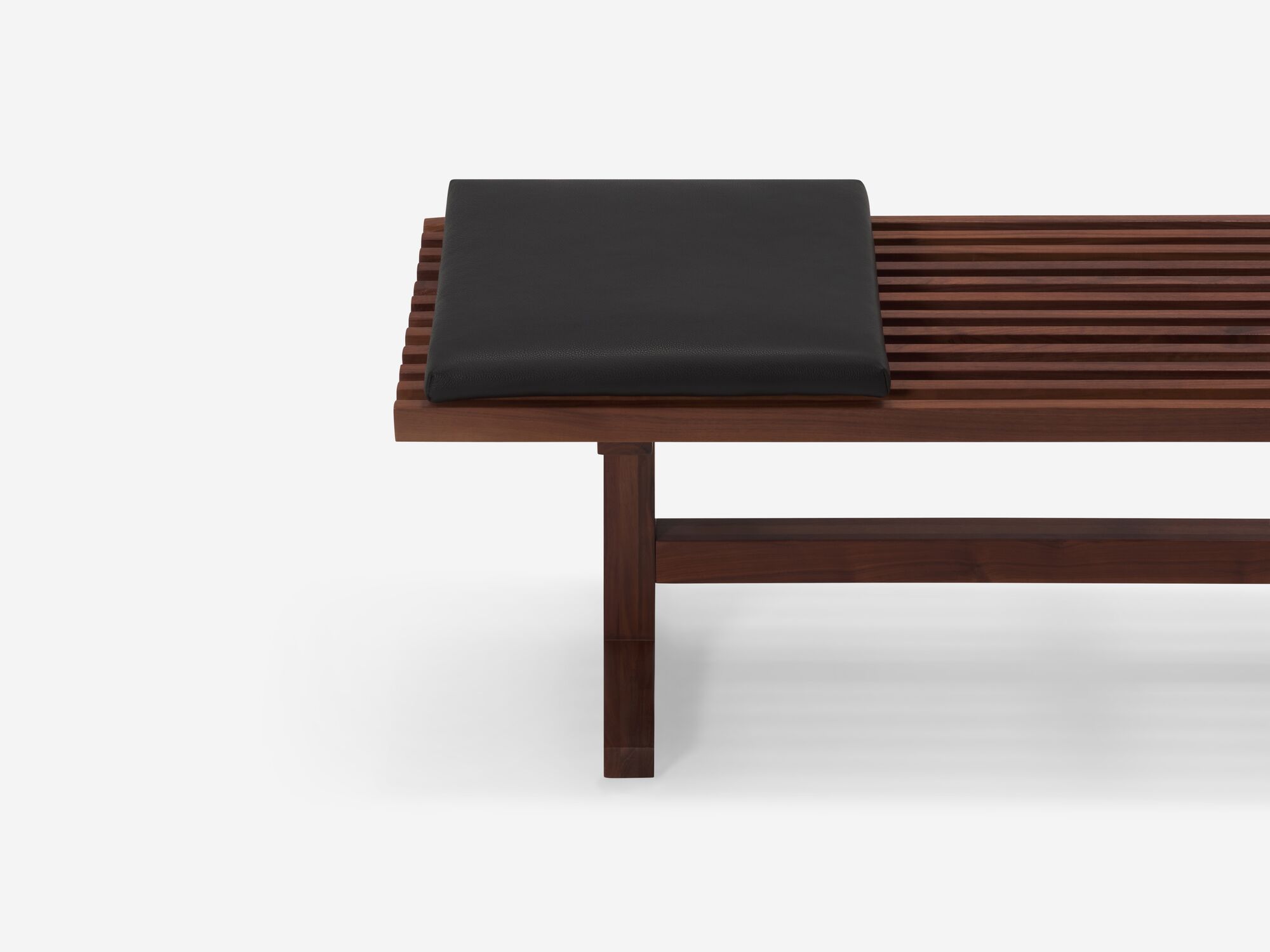 Square black leather cushion on walnut bench side detail view