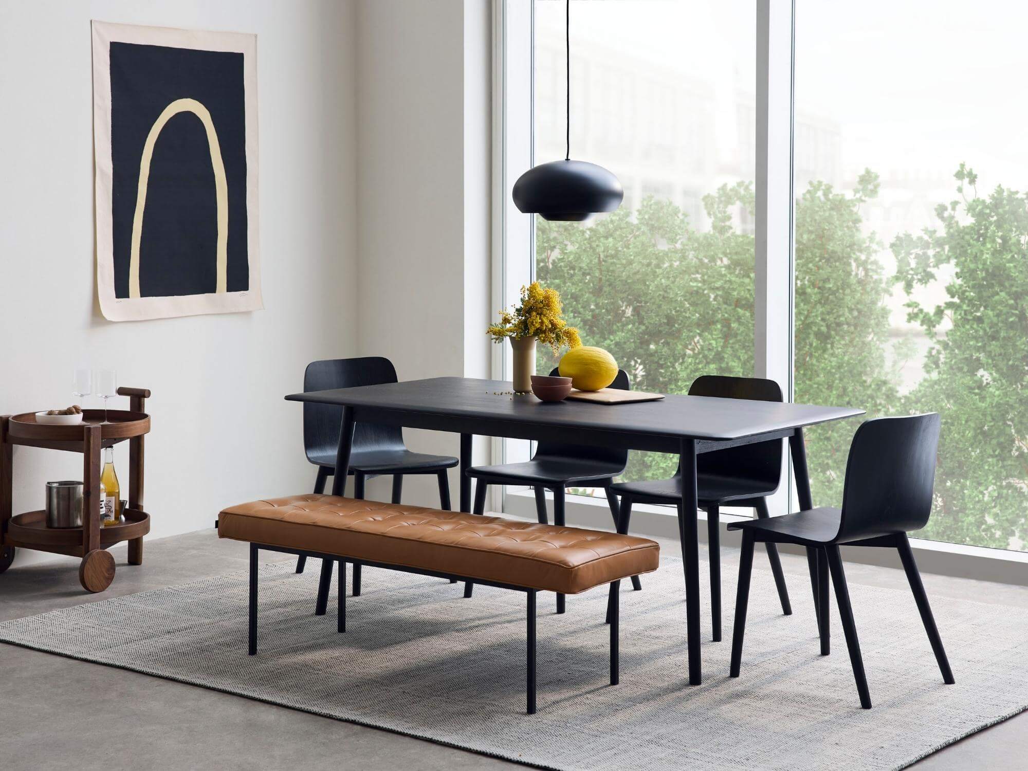 Gray rug under black dining set with brown leather bench