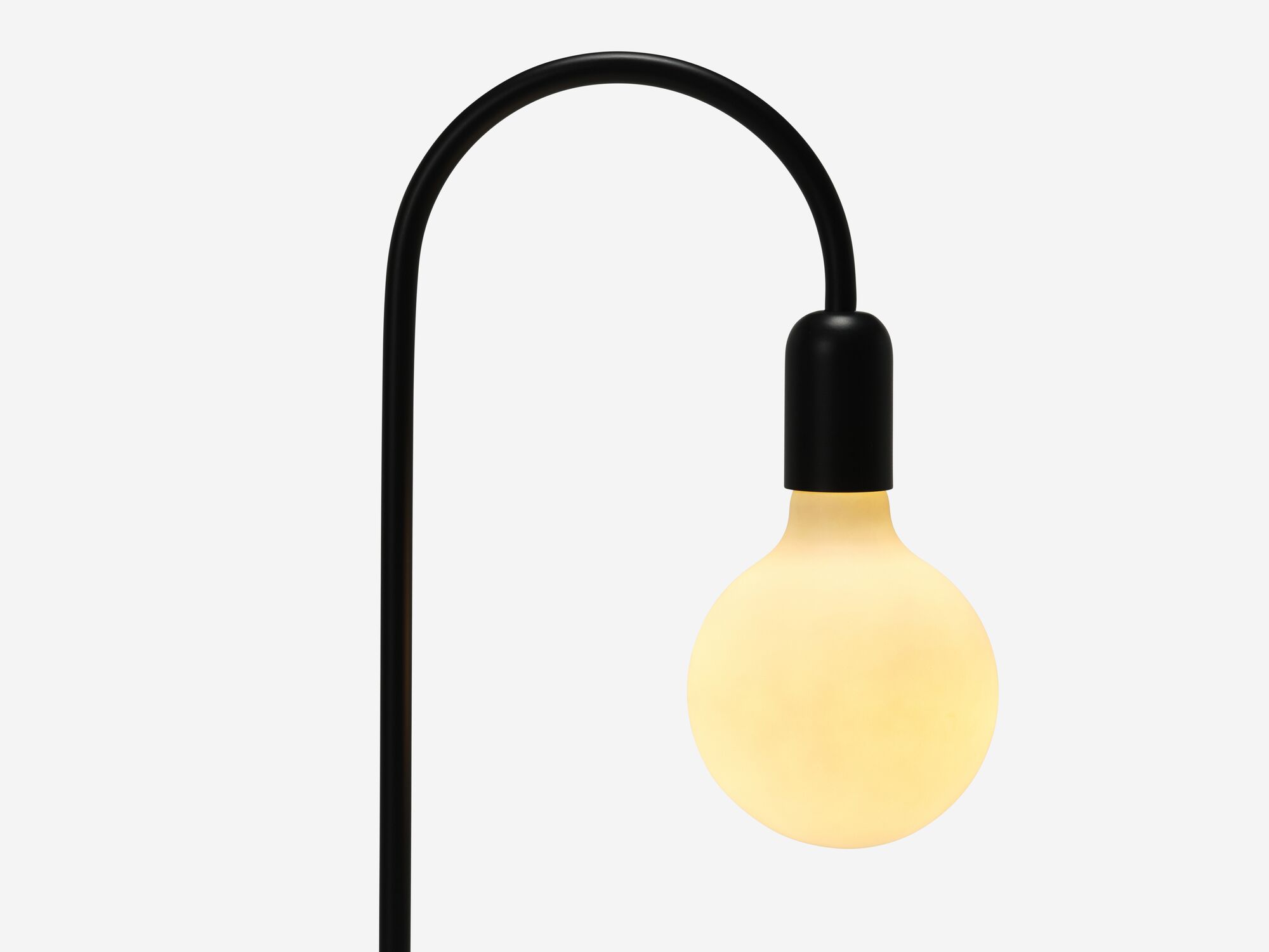 Black curved table lamp with light on detail bulb view