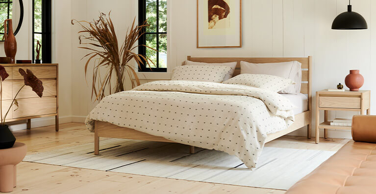 Oak bed with white bedding is shown in a bedroom setting. Link to bedroom category