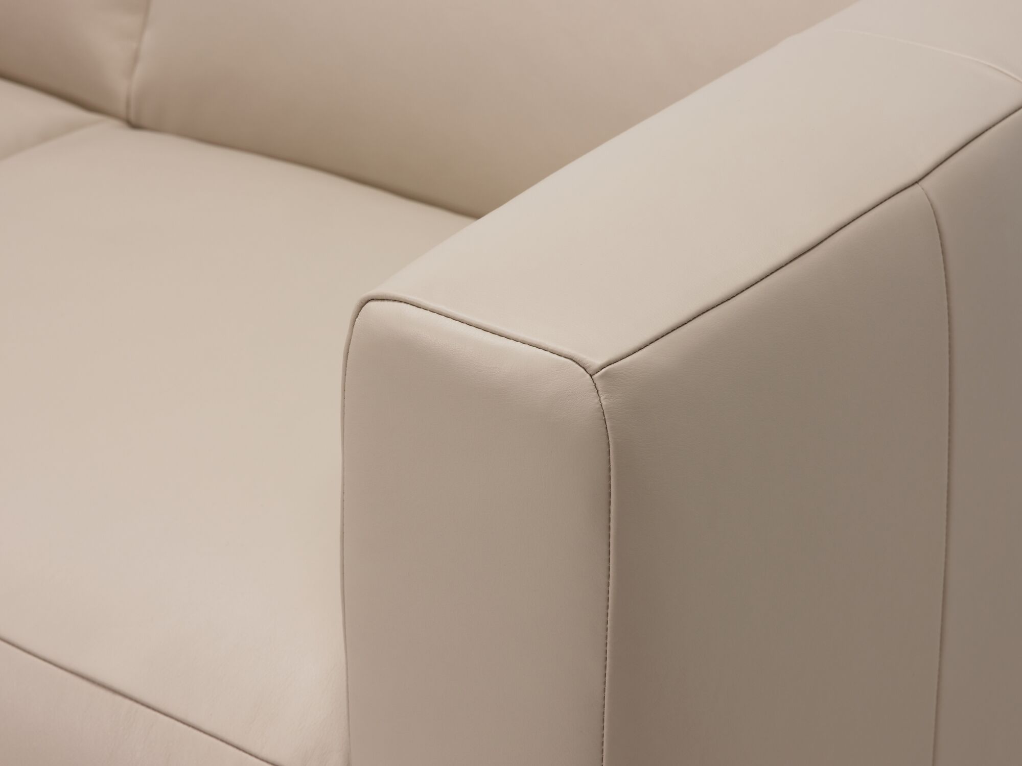 Arm detail view of beige leather sectional