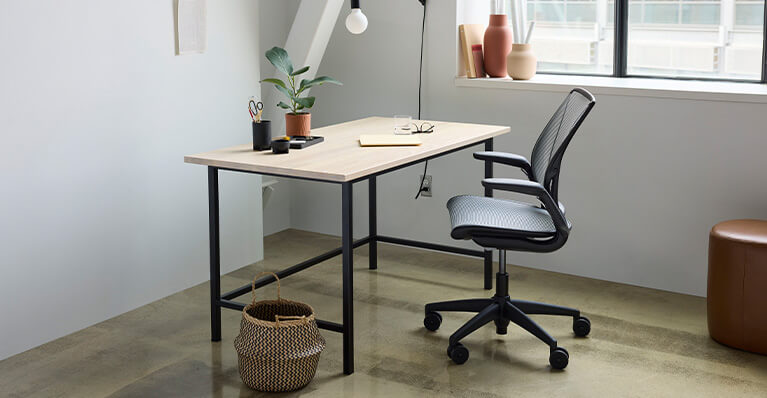 Ash top desk and grey office chair are displayed in a home office setting. Link to Humanscale category