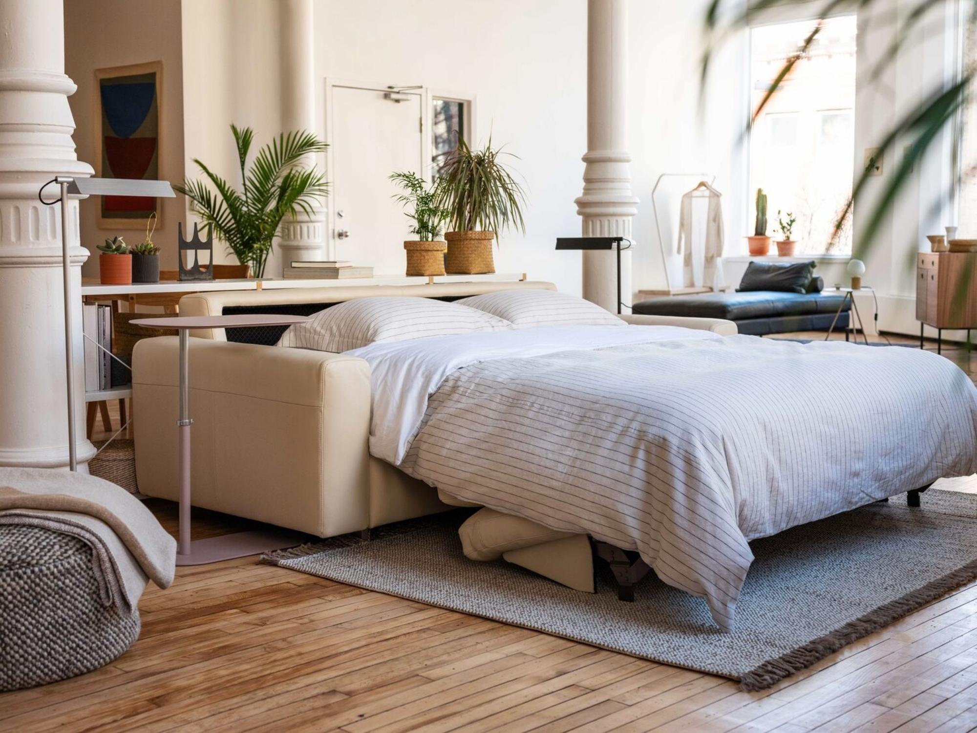 Beige leather sofa bed with matching duvet cover set in loft living space