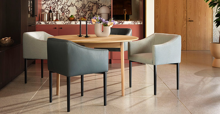 three square leather dining chairs are shown around a round dining table. Link to ease product search page