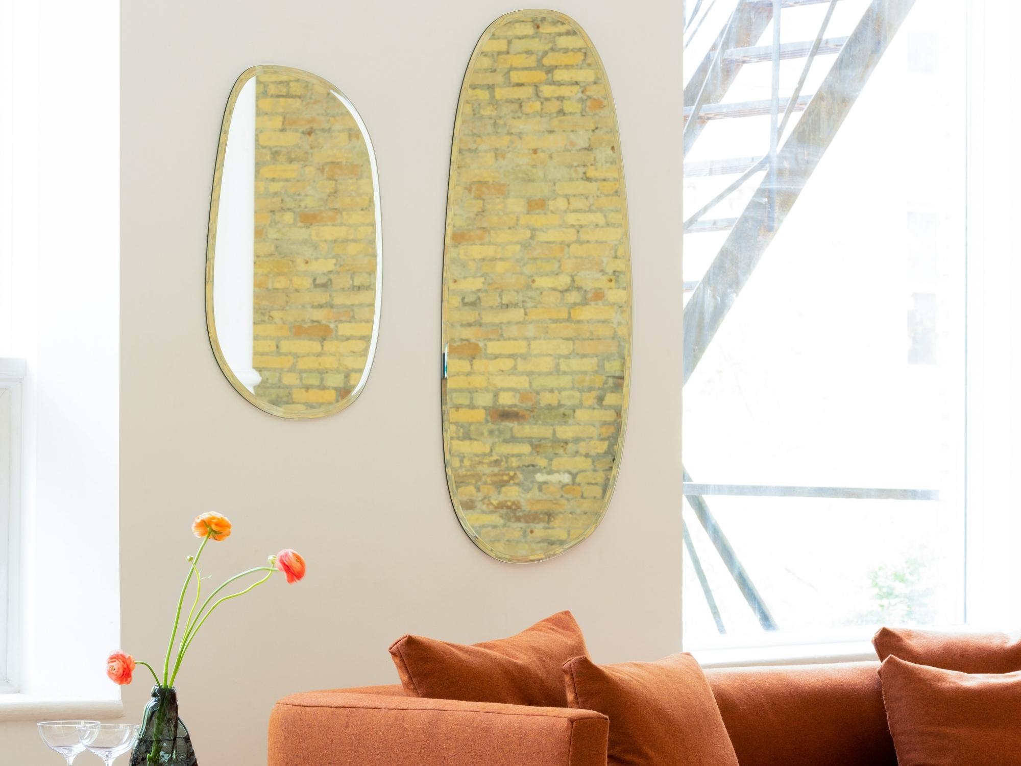 Wall mirrors over red modern sofa and walnut bar cart