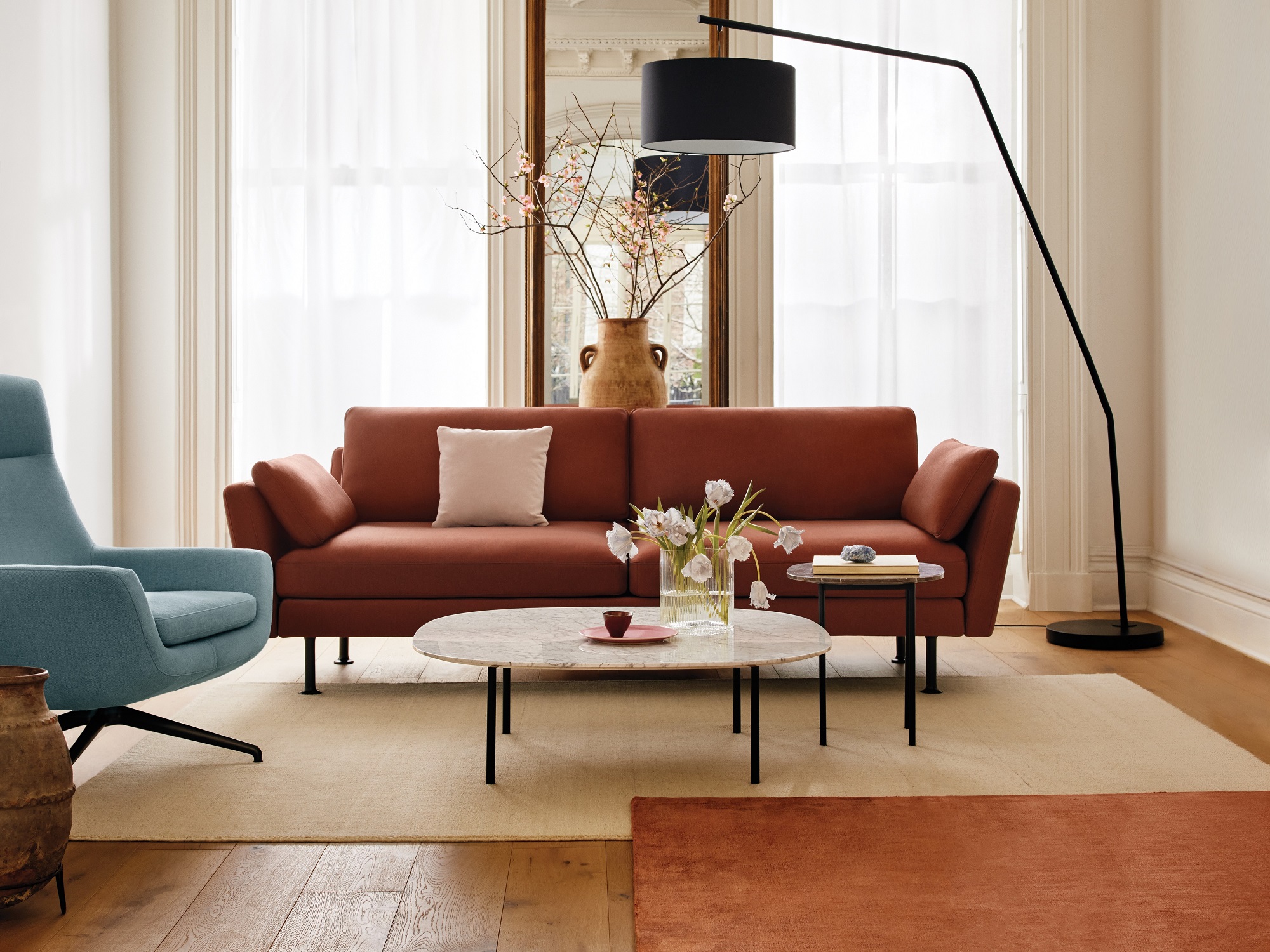 Rust red sofa with arch floor lamp and blue lounge chair in modern living space