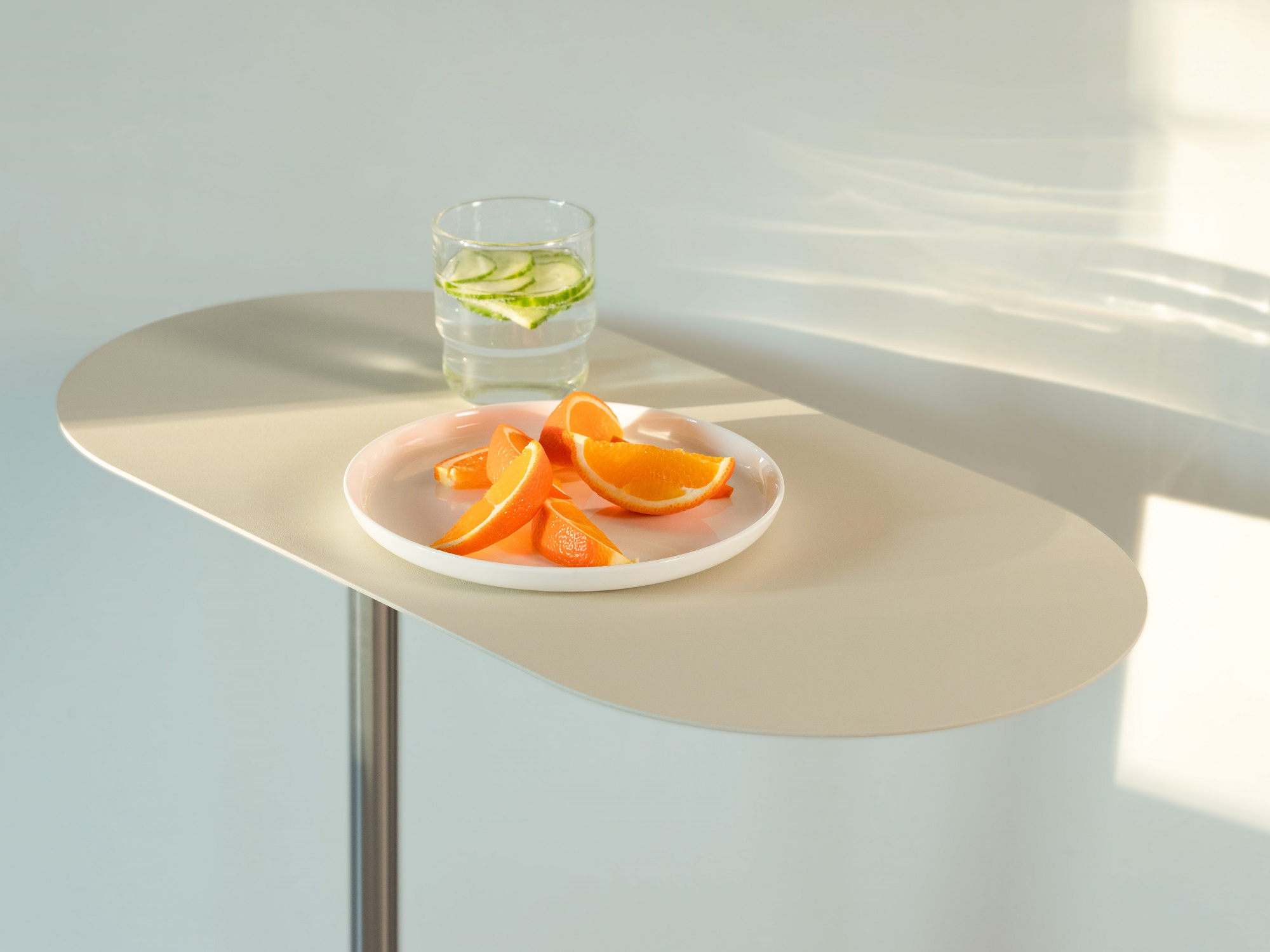 The Finn floating end table with a plate of orange slices and a glass of cucumber water on it, beside a white wall