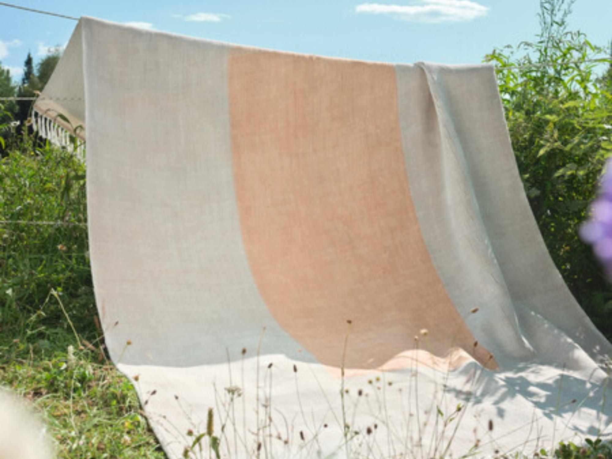 Beige and peach area rug tossed over an outdoor laundry line