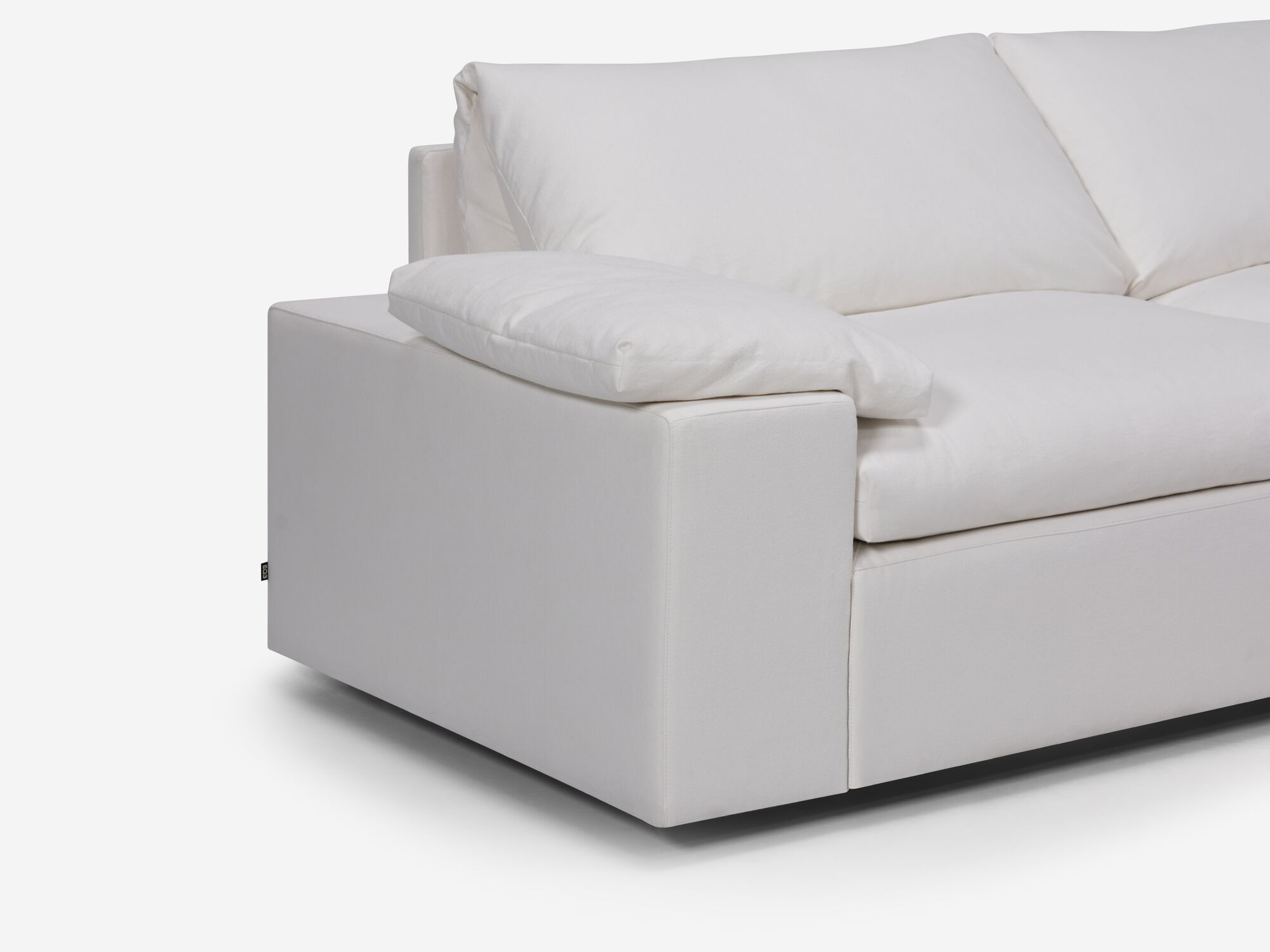White sectional sofa with right hand chaise, pillow and wide arms seat detail view