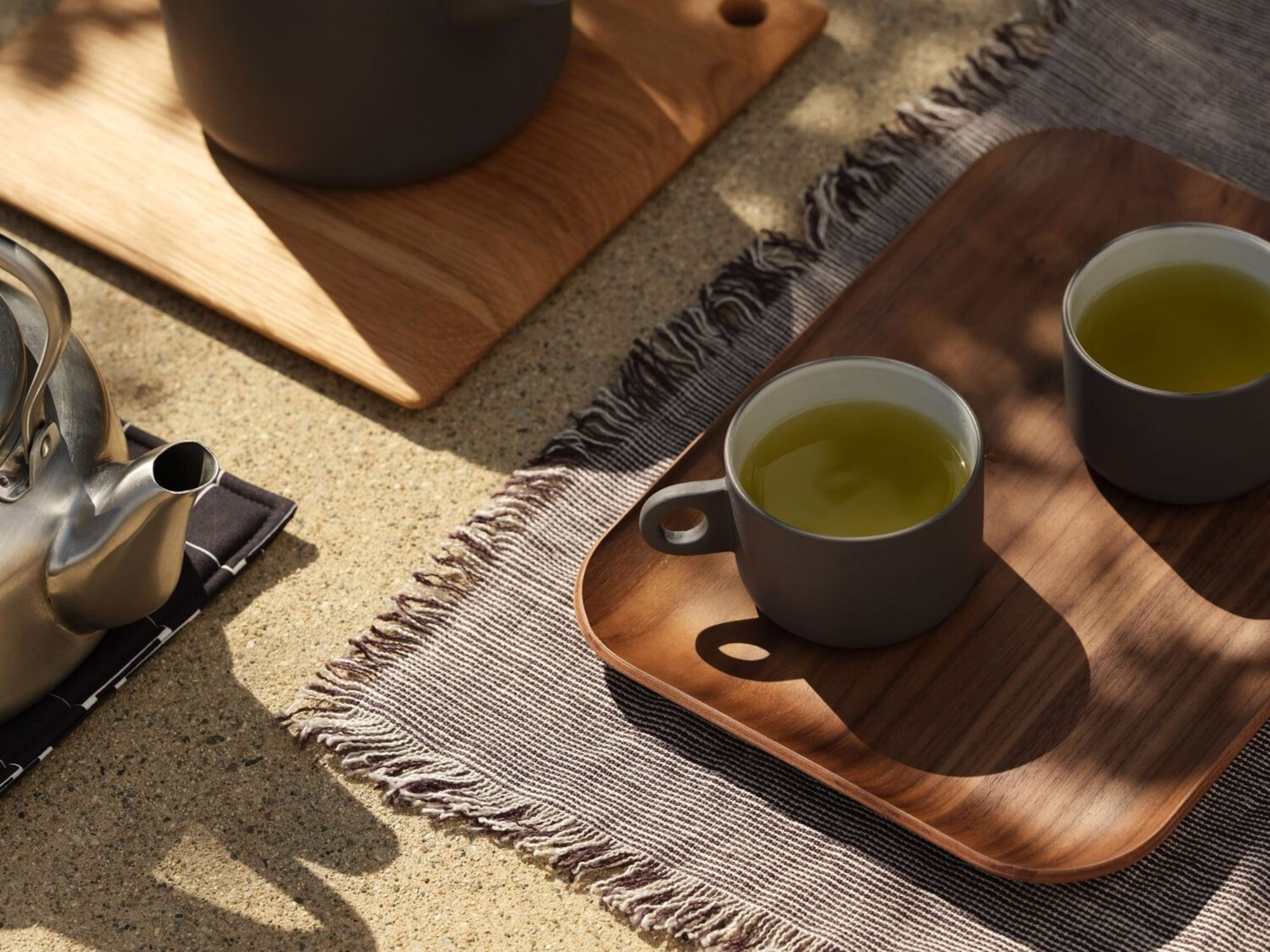 Grey stoneware mugs with matching tea pot on outdoor table