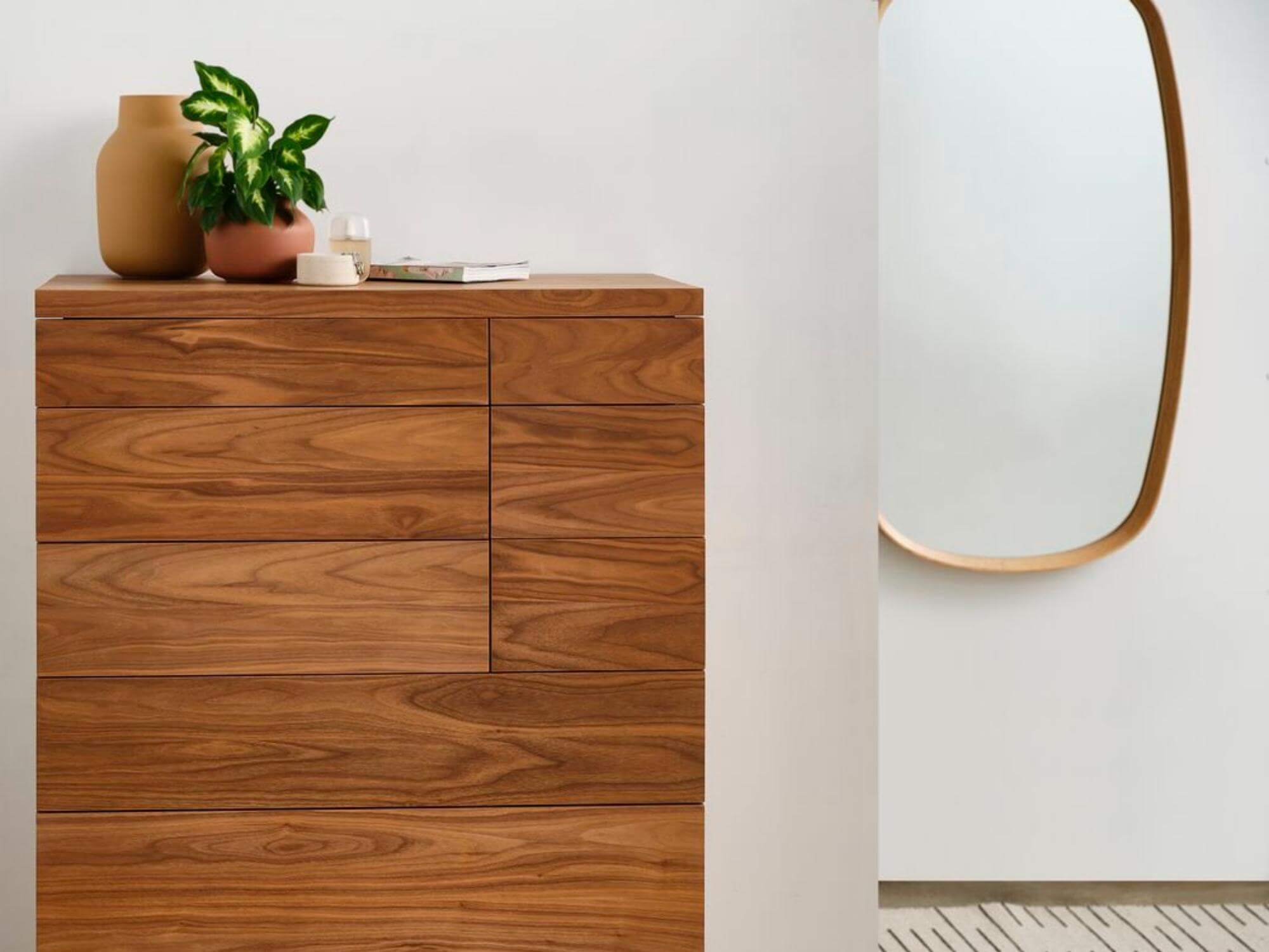 Wood frame oval mirror above runner rug in modern bedroom