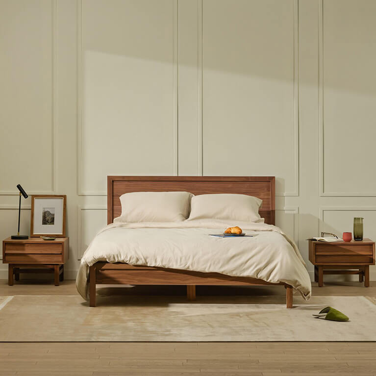 A queen walnut bed and matching storage is displayed in a modern bedroom. Link to room bundles