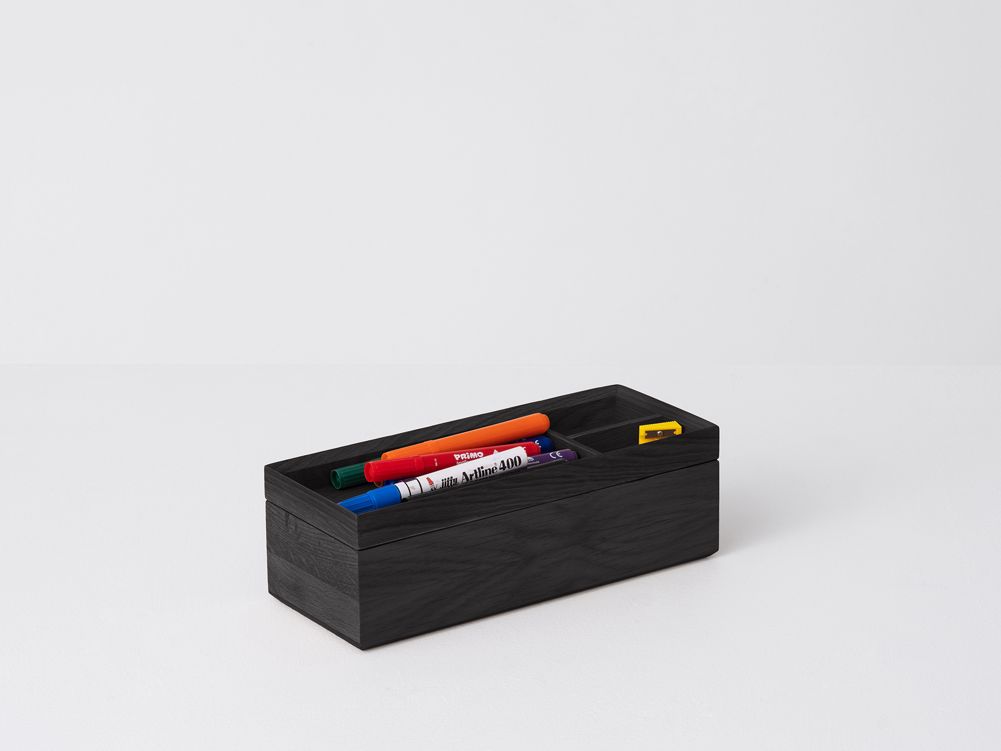 Angled view of the large wooden Draft Pencil Box in black oak with pencils in the top