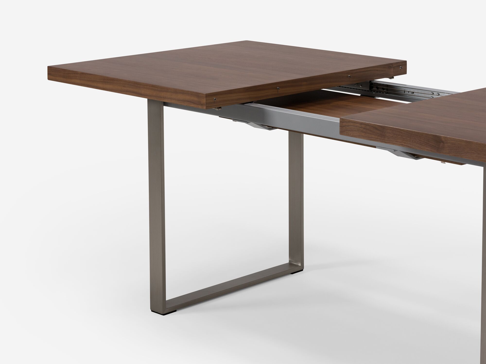 Expandable dining table with stainless steel legs and walnut top detail view