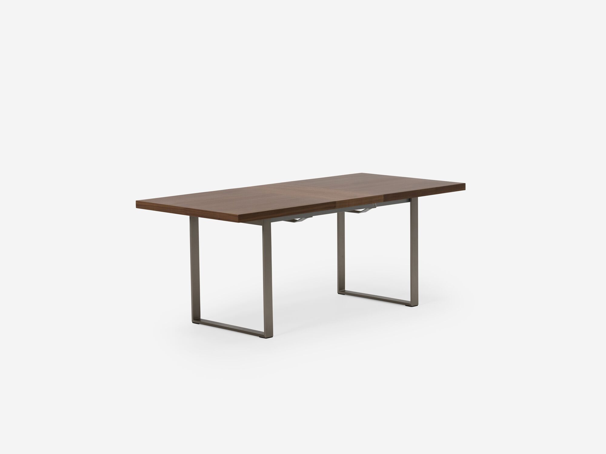 Corner view of expandable dining table with stainless steel legs, walnut top and one leaf