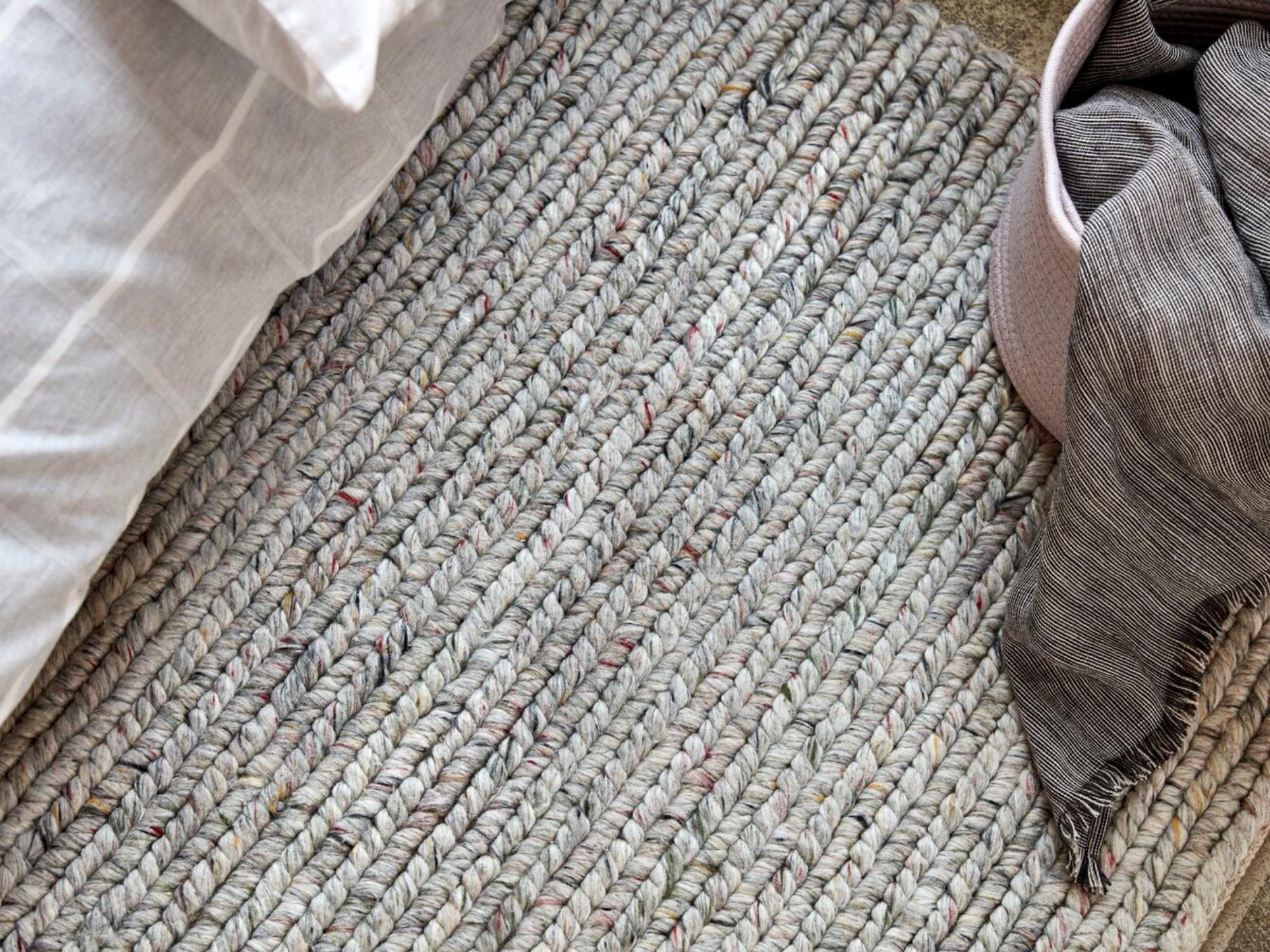 Braided area rug between basket with throw and bed covers