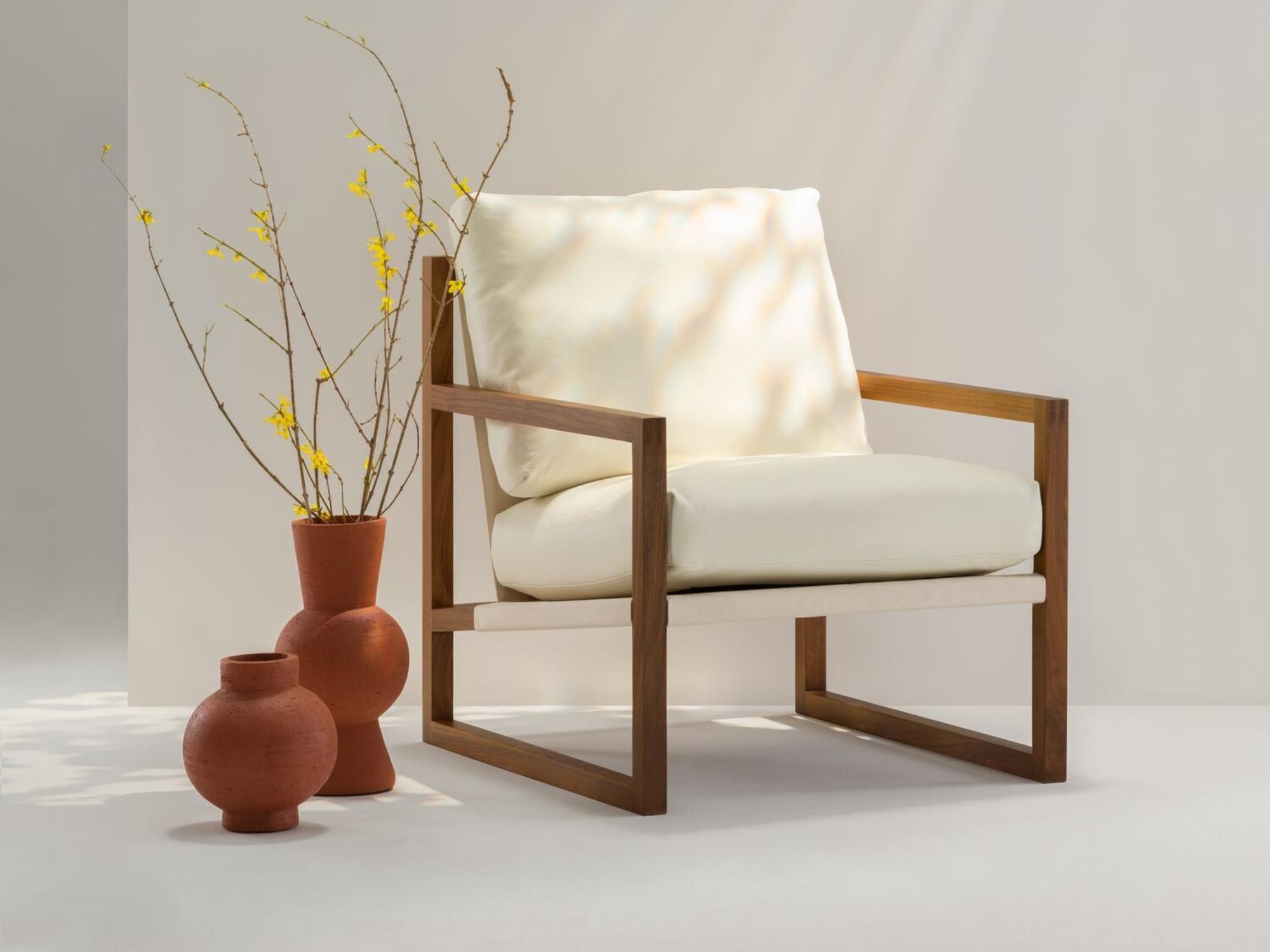 Round and tall terracotta vases next to beige armchair