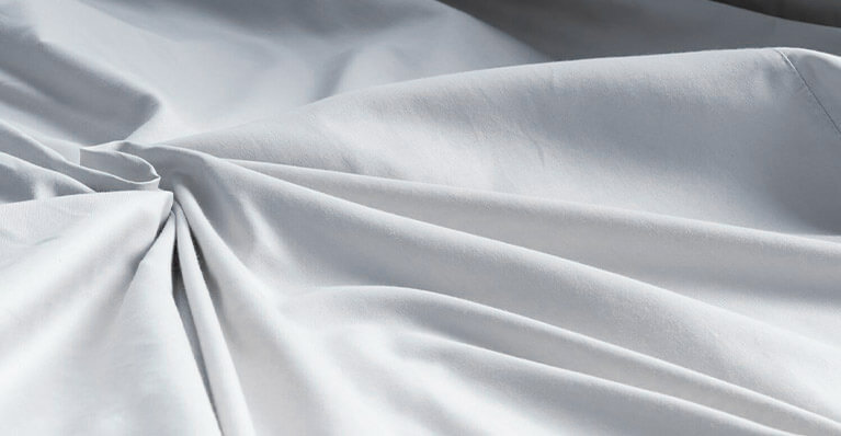 a light grey sheet is shown in up close detail. Link to bedding promotion page