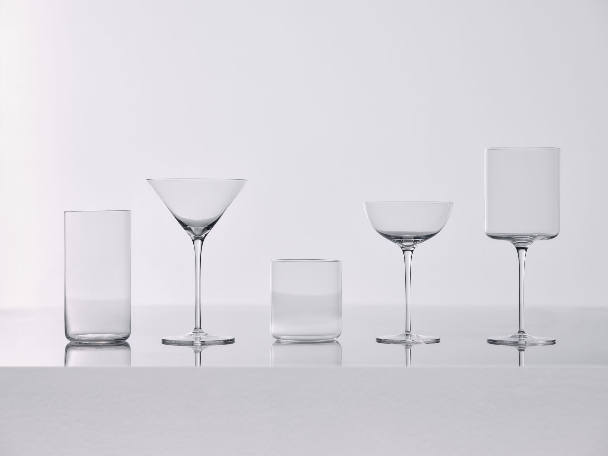 A collection of Vesper glasses with liquid in them on a white table