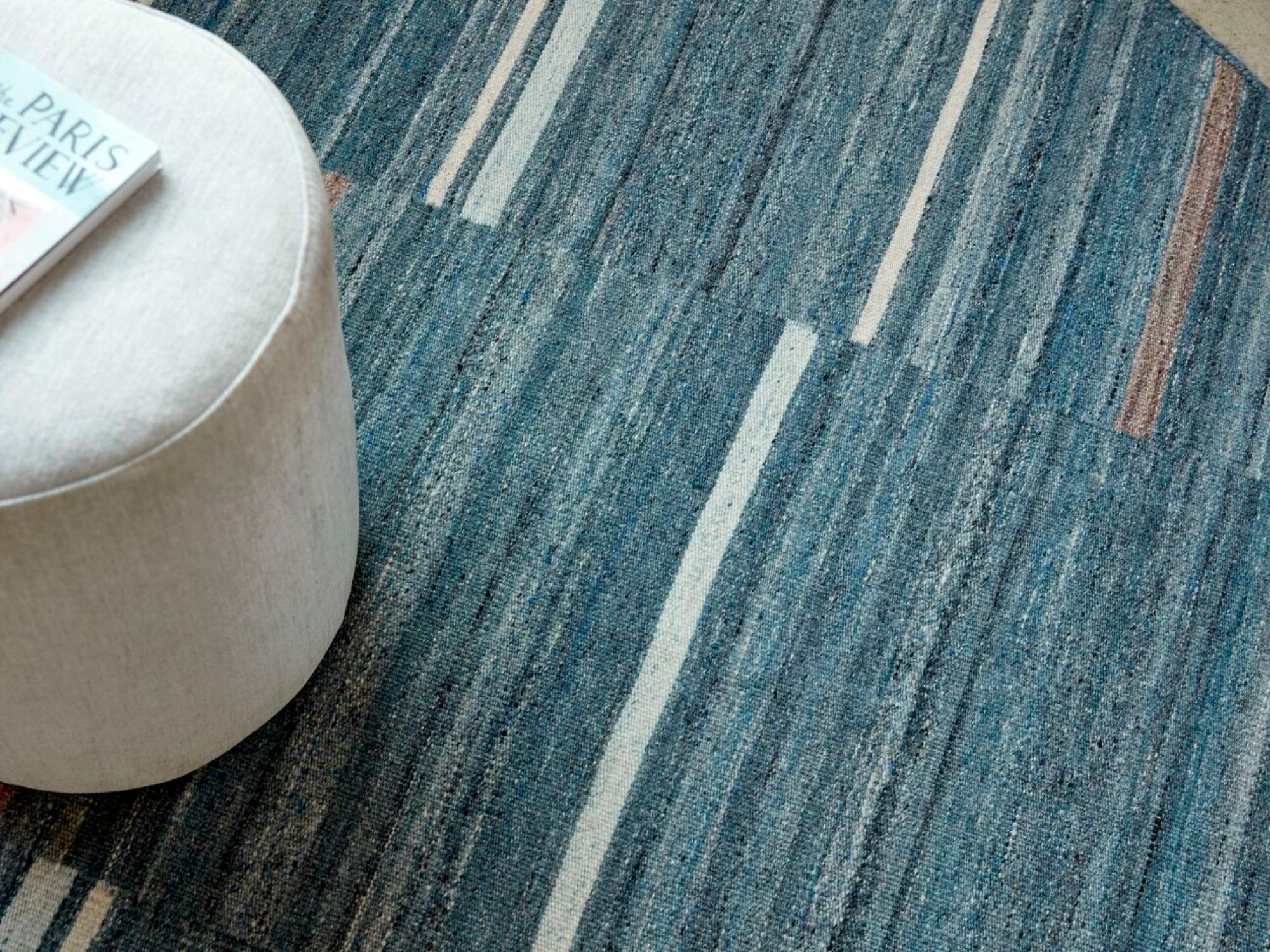 Beige round ottoman on round blue striped rug