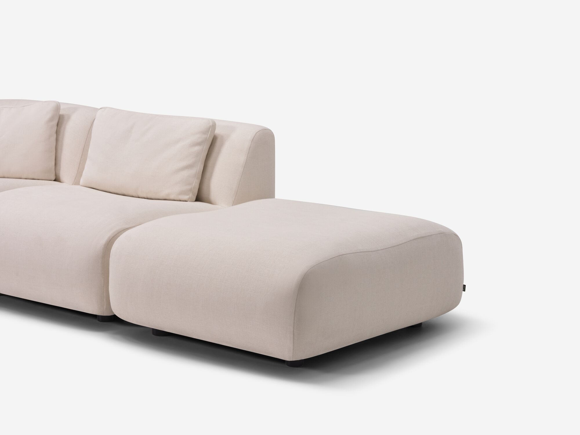 Chaise detail view of beige armless sectional sofa