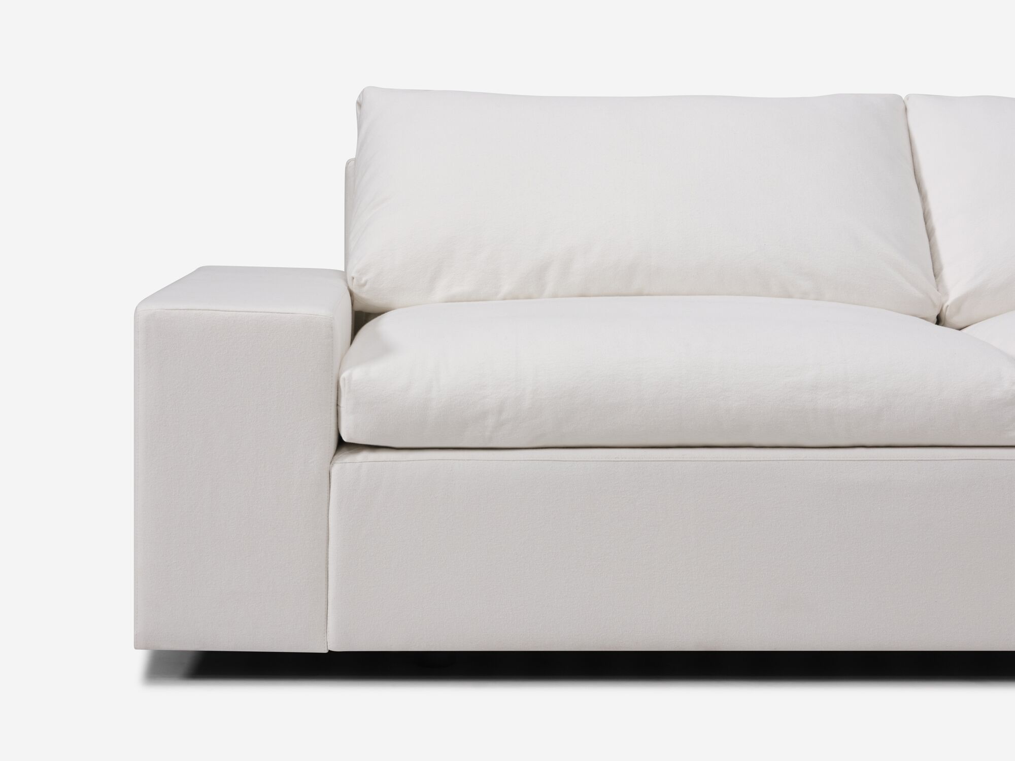 Detail view of white sectional sofa with right hand chaise and wide arms