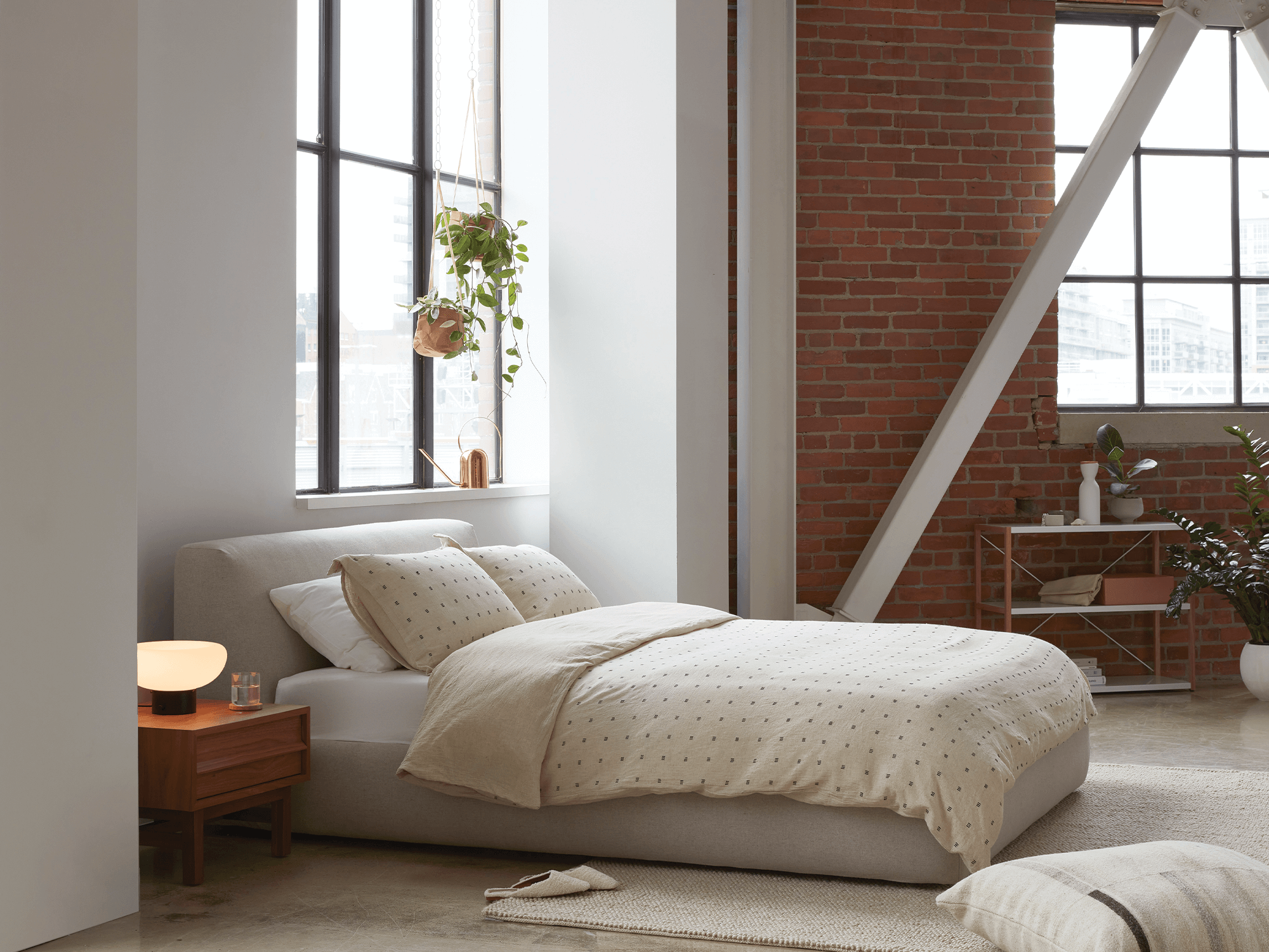 Beige wool rug under a gray upholstered bed and beige duvet set