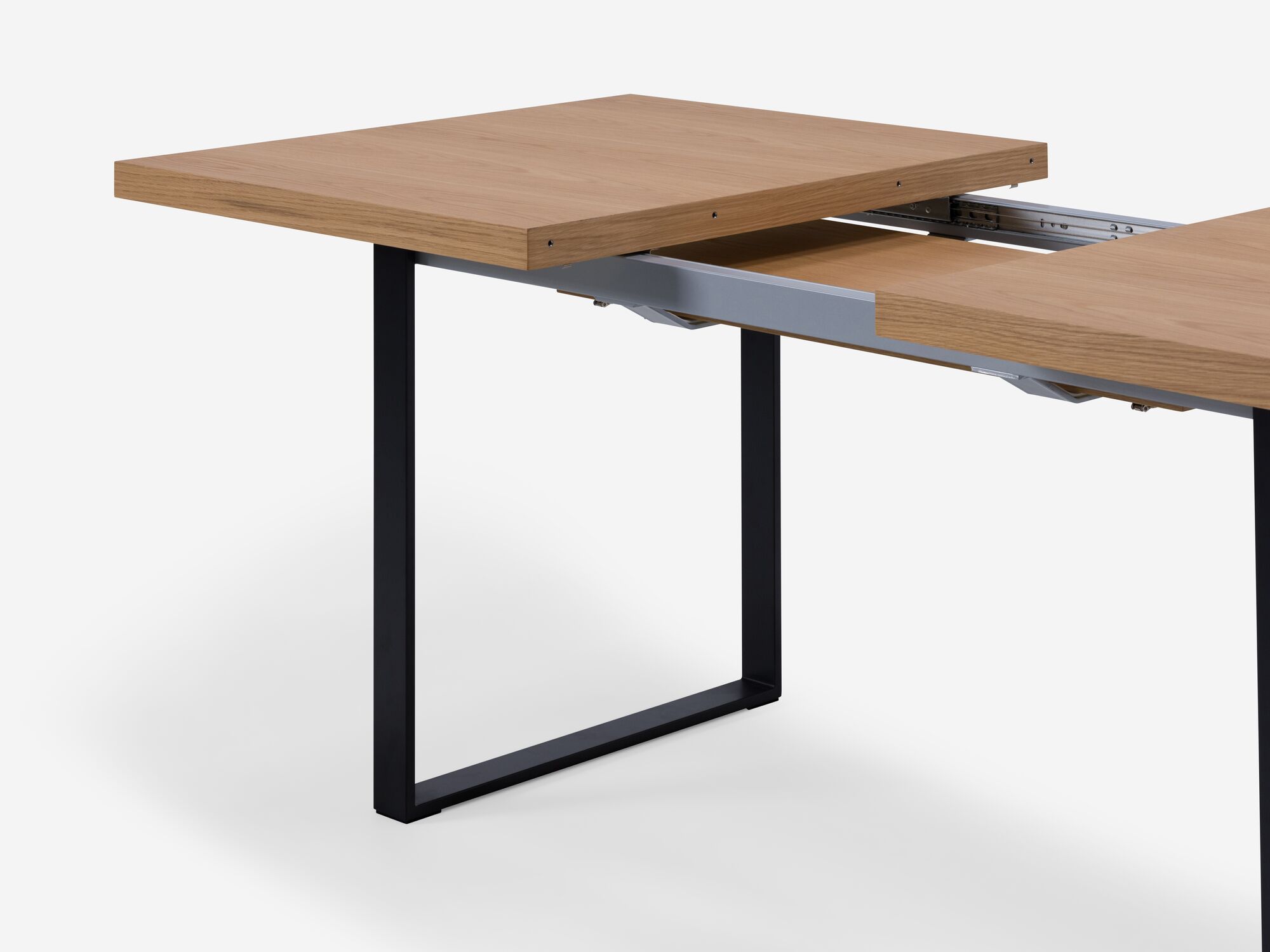 Detail view of expandable dining table with black legs and oak top