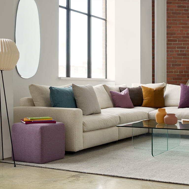Large beige fabric sectional is displayed in a studio living room. Link to sectionals