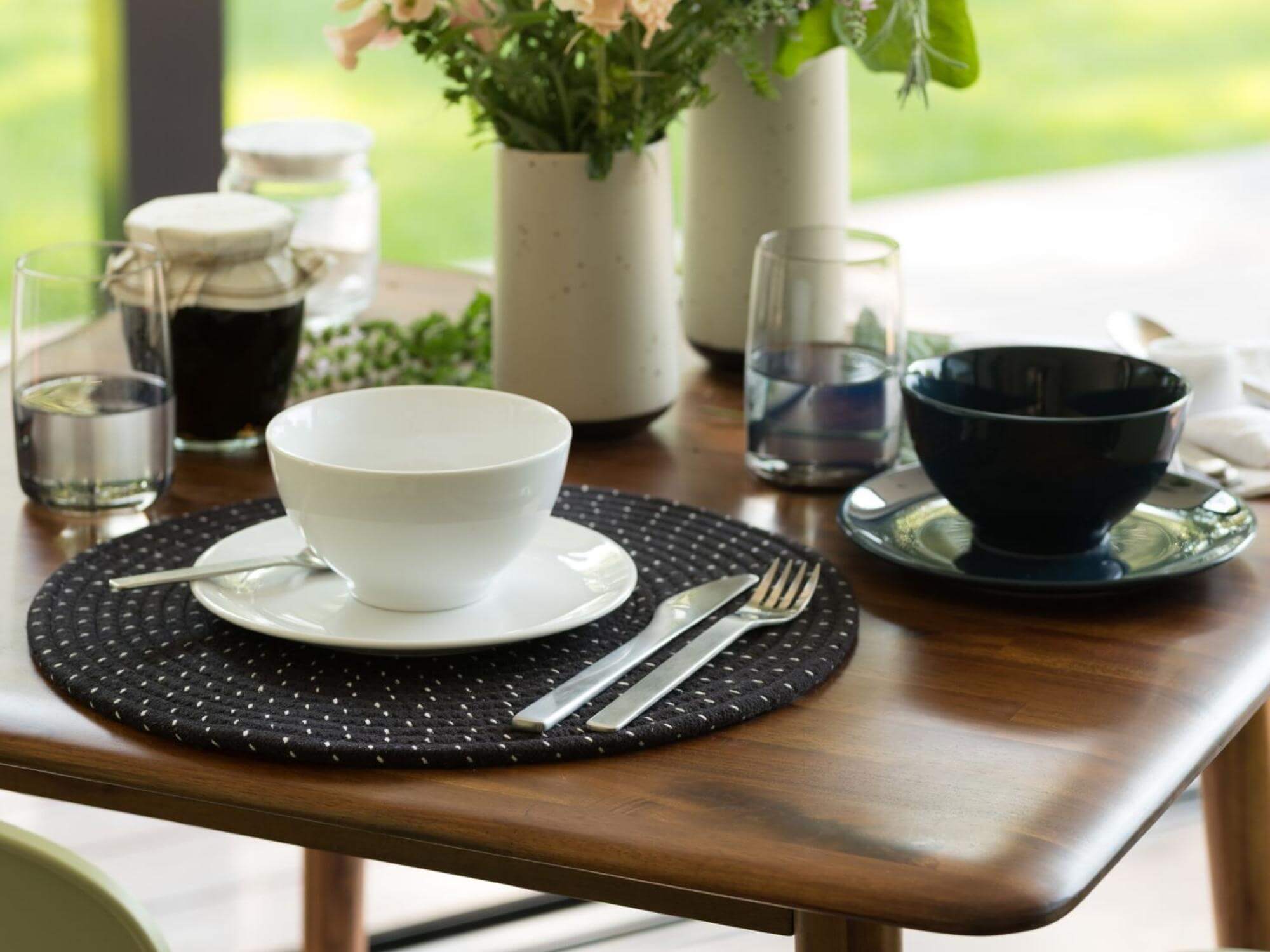 Grey glass highball with place setting on walnut dining room table