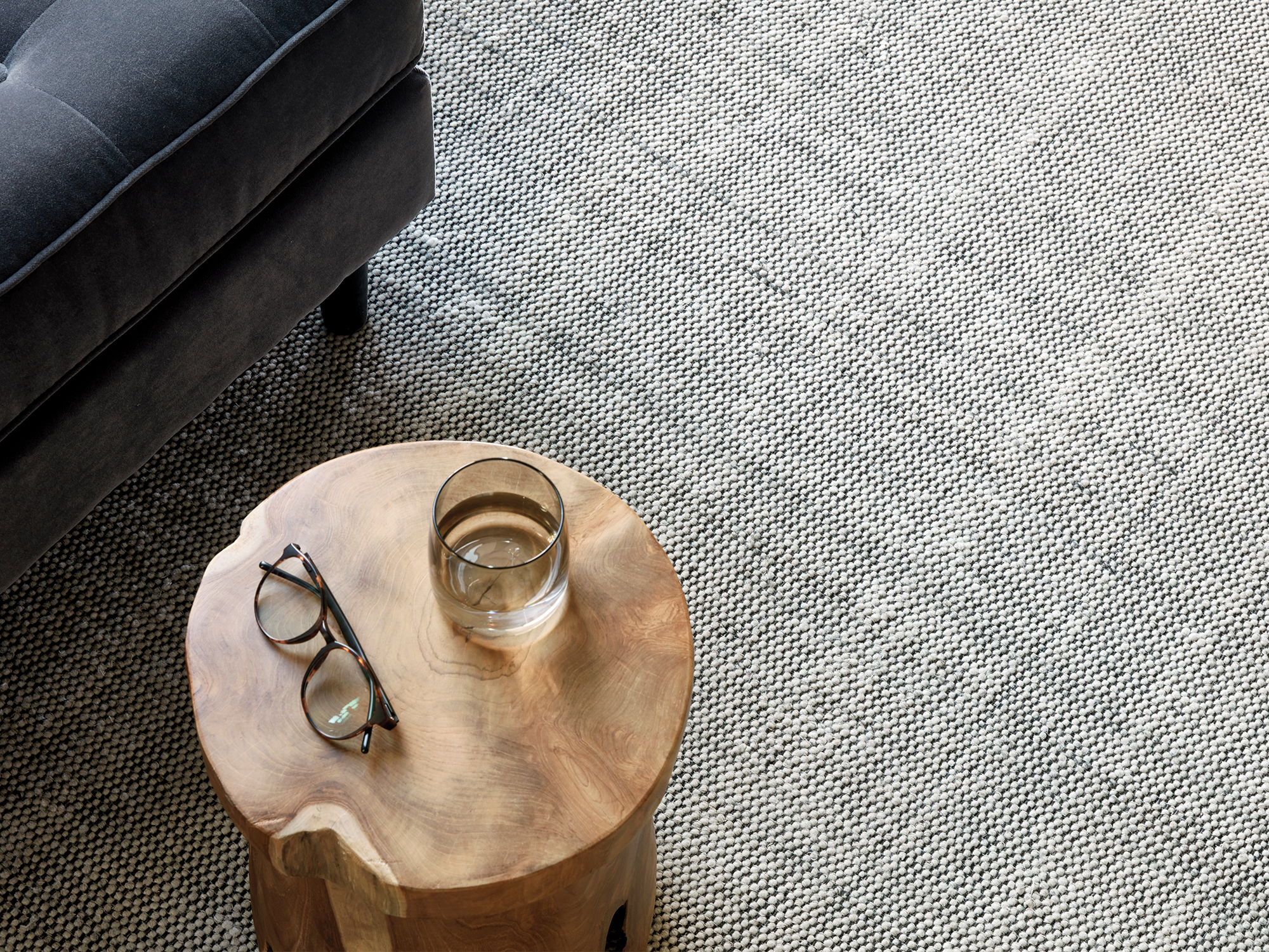 Gray living room rug with a gray sofa and teak stool on it