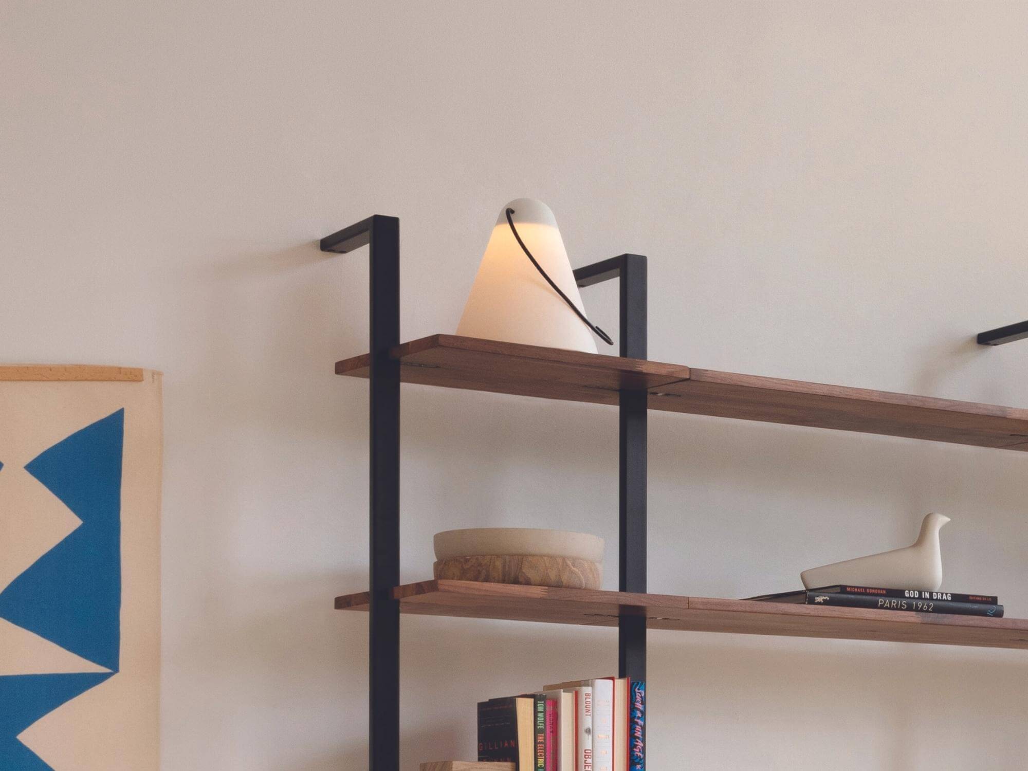 Conical table lamp on shelf of open bookcase in home office