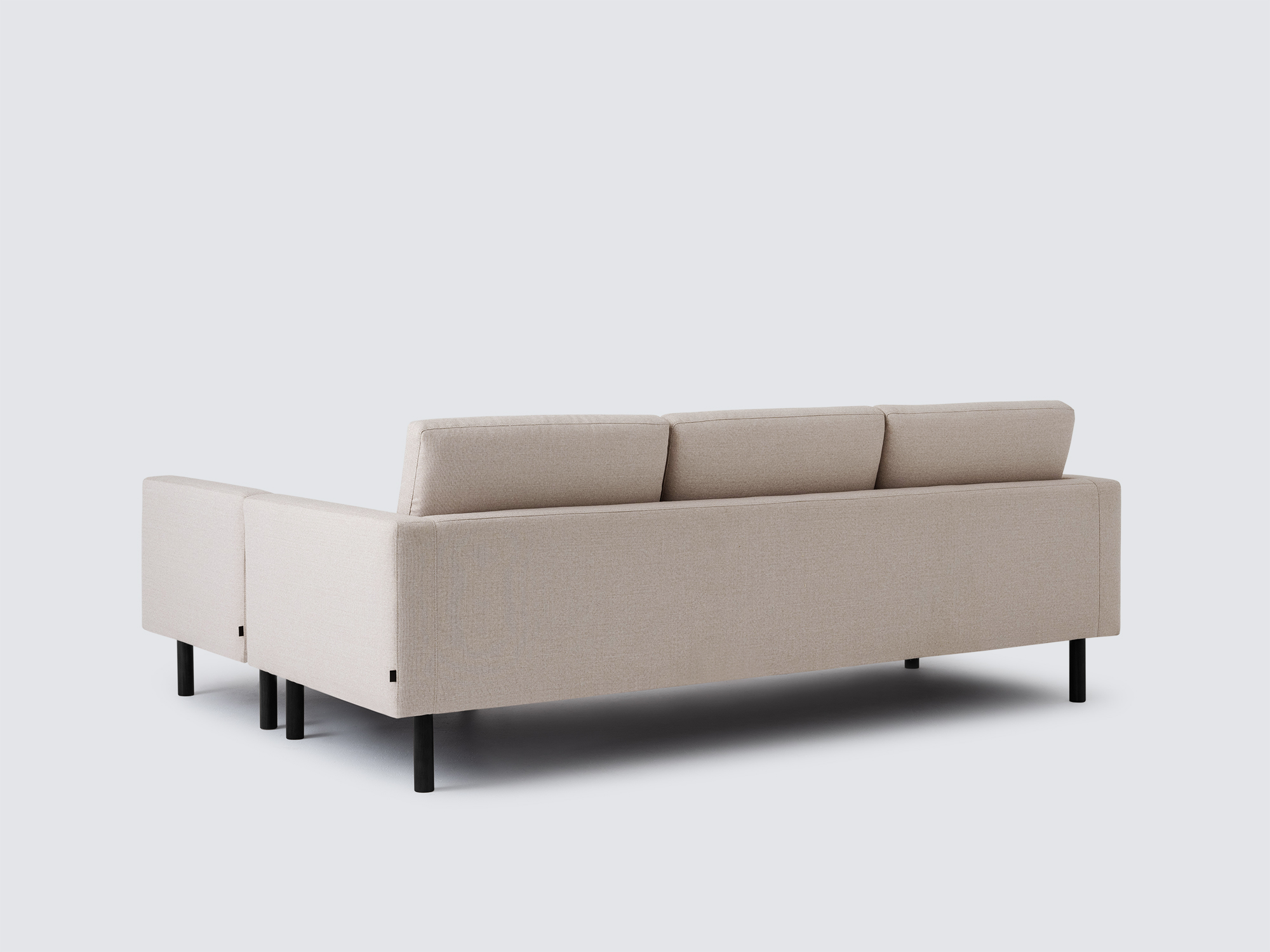 Back angled view of the Joan left hand sectional upholstered in beige fabric