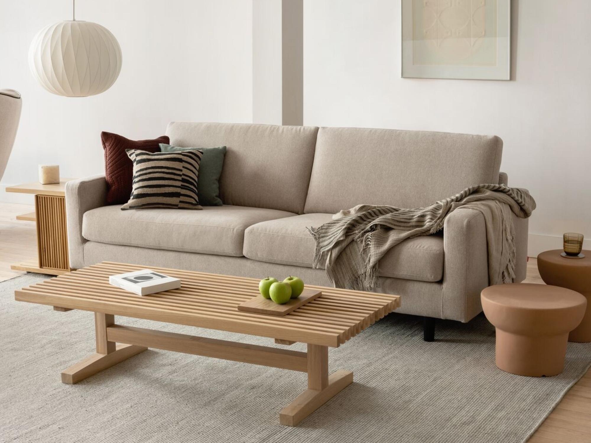 Black and beige pillow on beige sofa with oak slatted coffee table in living space