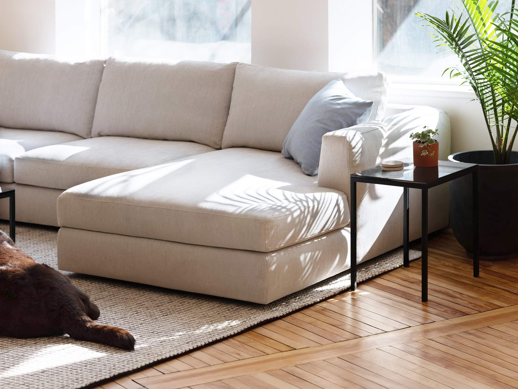 Black marble side table beside ivory sectional in modern living room