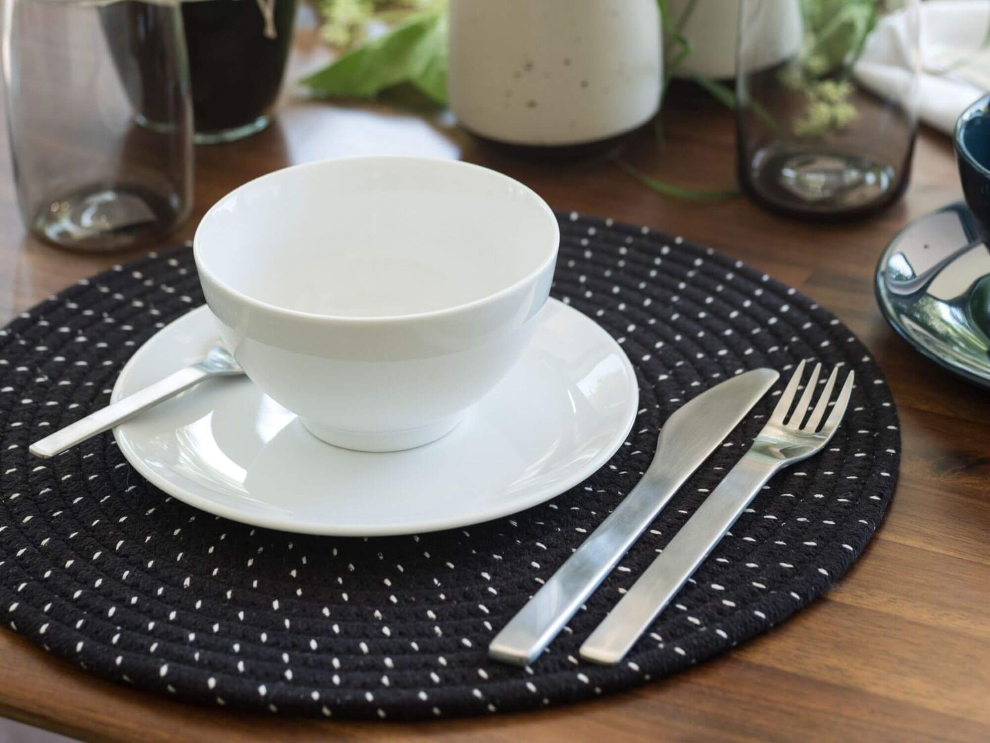 White side plate with matching bowl and black platemat on dining table