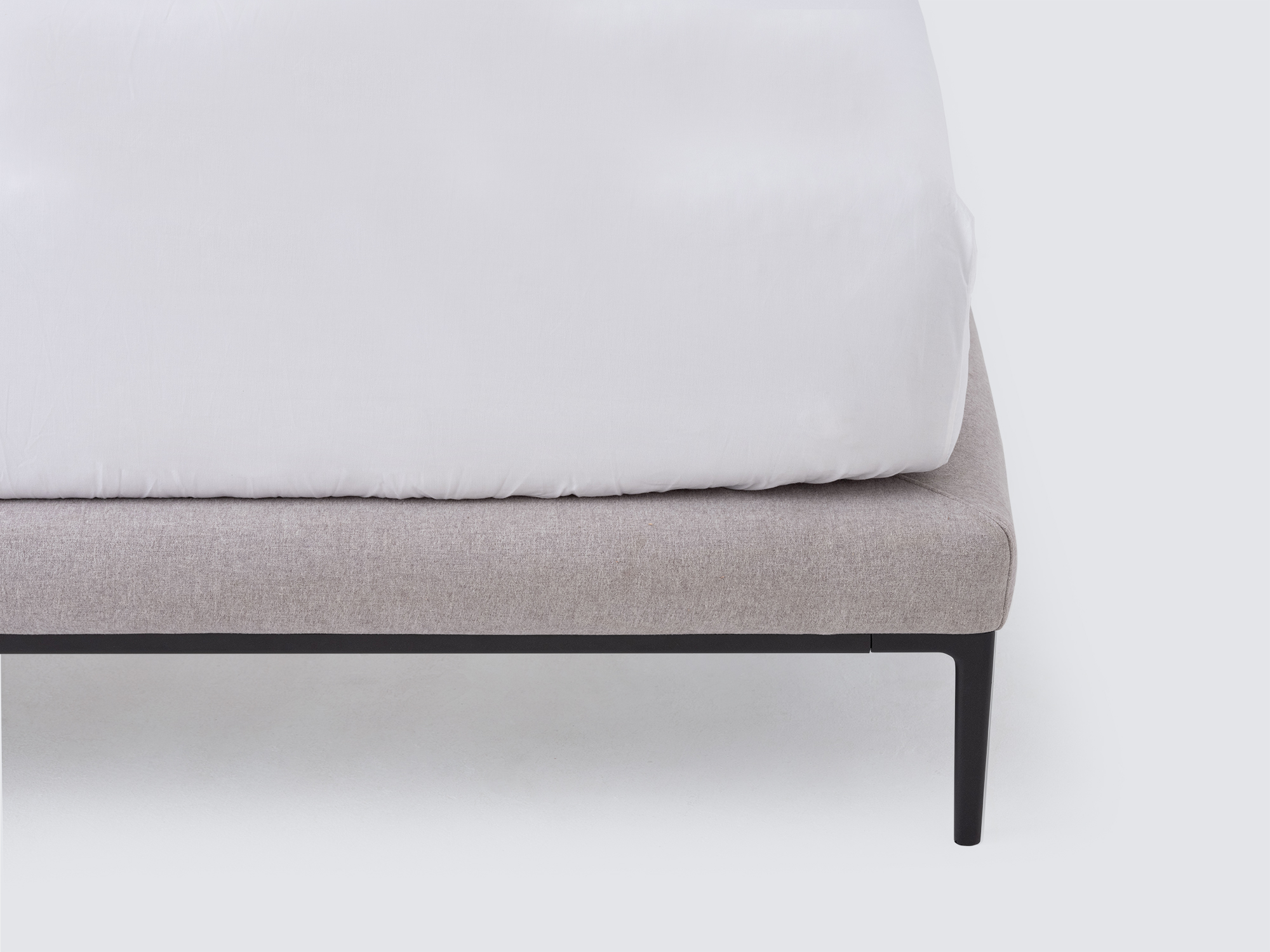 Corner view of the Oma upholstered bed in gray fabric